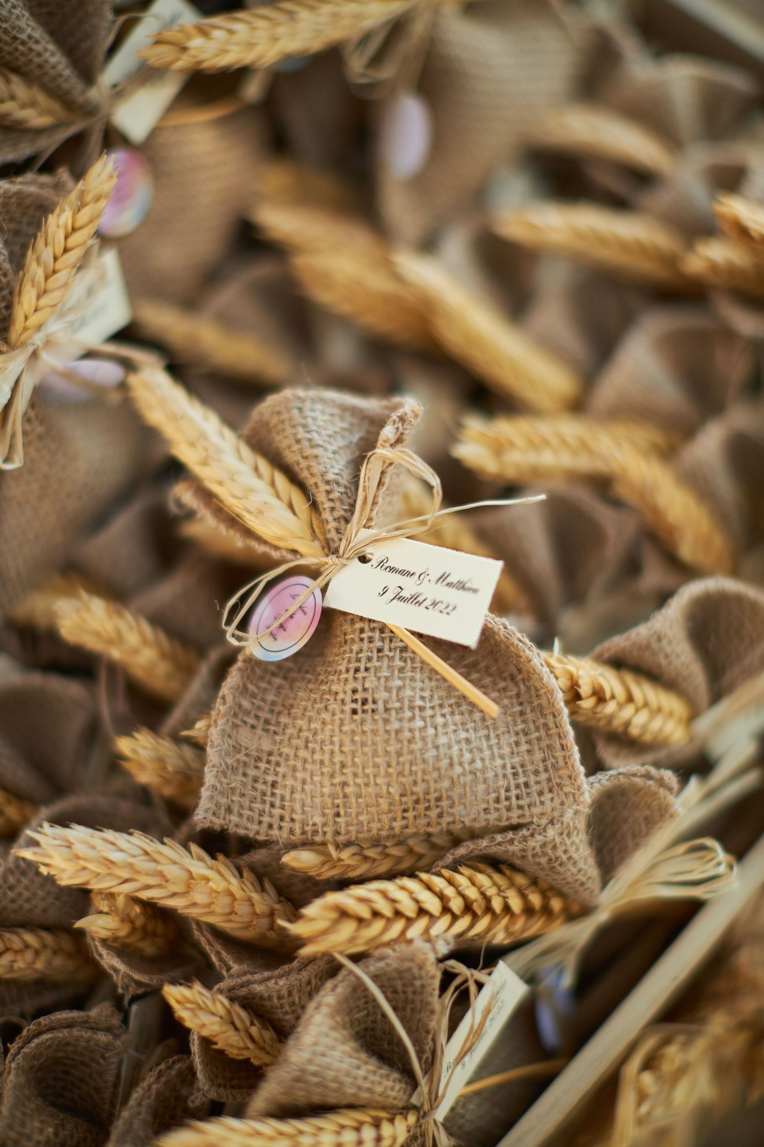 Rustic burlap wedding favor bags tied with wheat stalks and personalized gift tags.