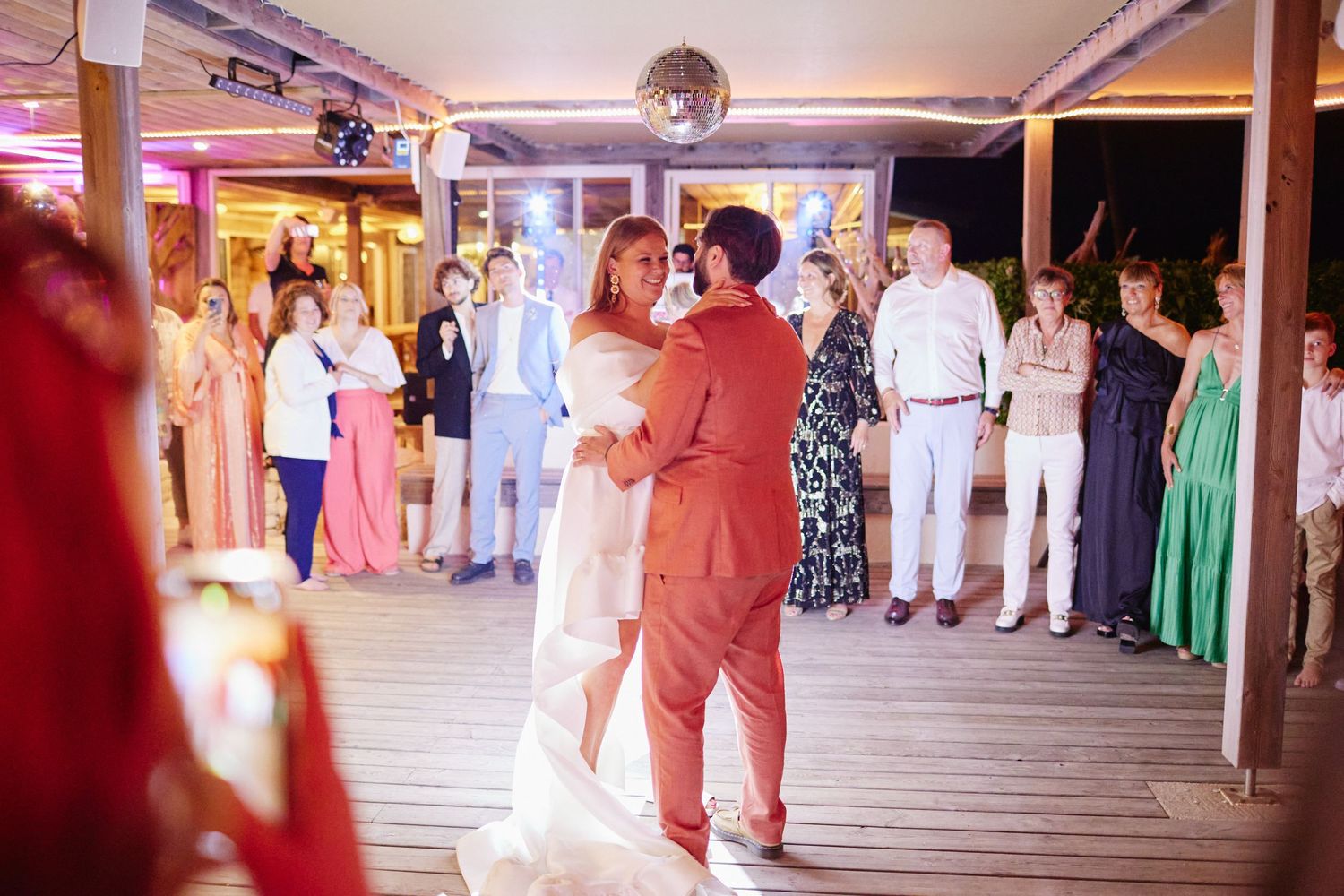 Bride and groom sharing first dance surrounded by wedding guests at elegant outdoor reception venue.