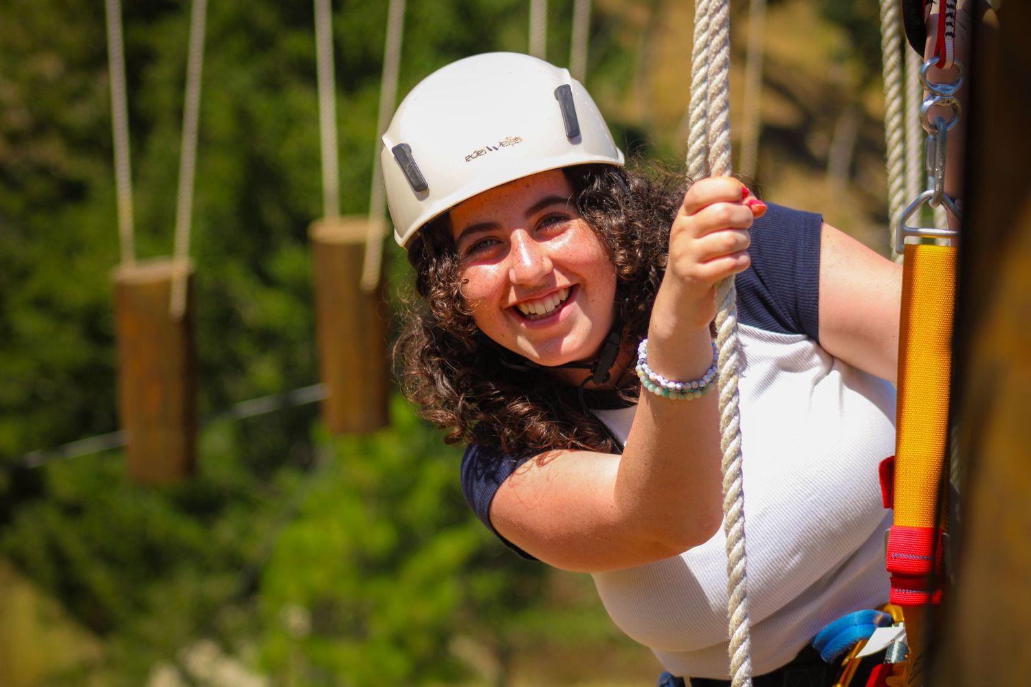 A girl with a helmet on doing a ropes course.
