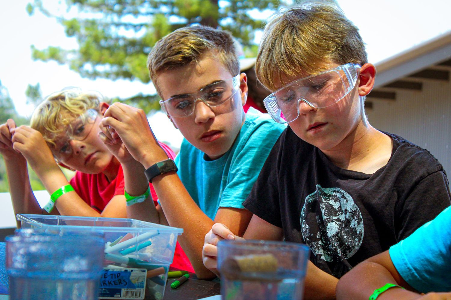 Three boys with lab goggles on doing an experiment.