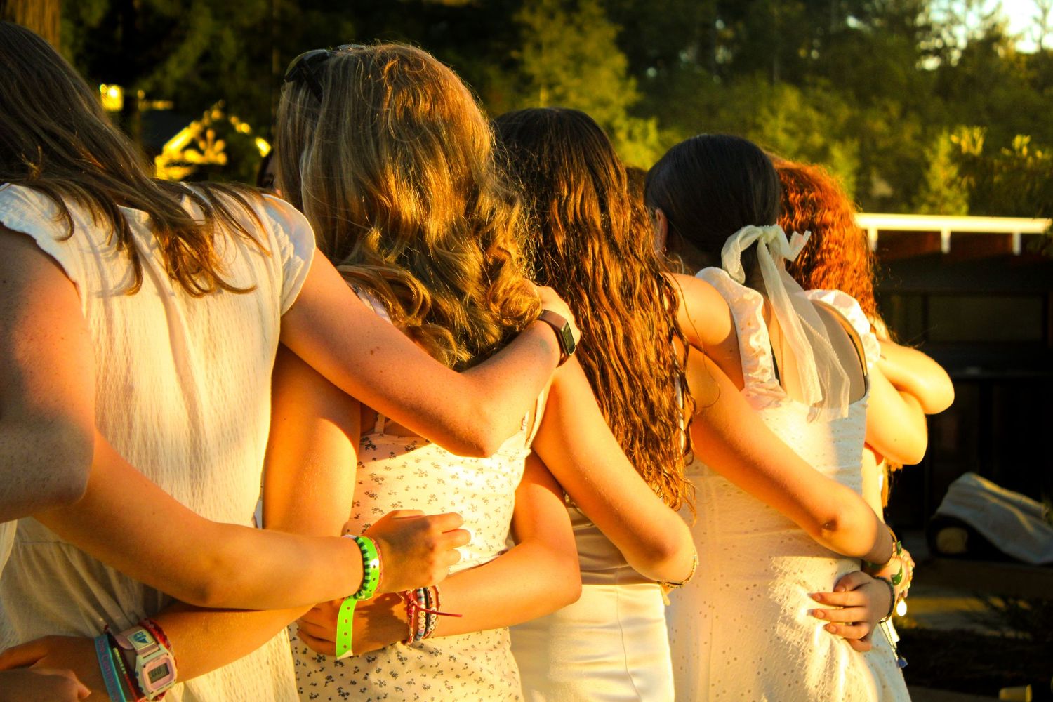 Girls with arms around each other in golden hour.