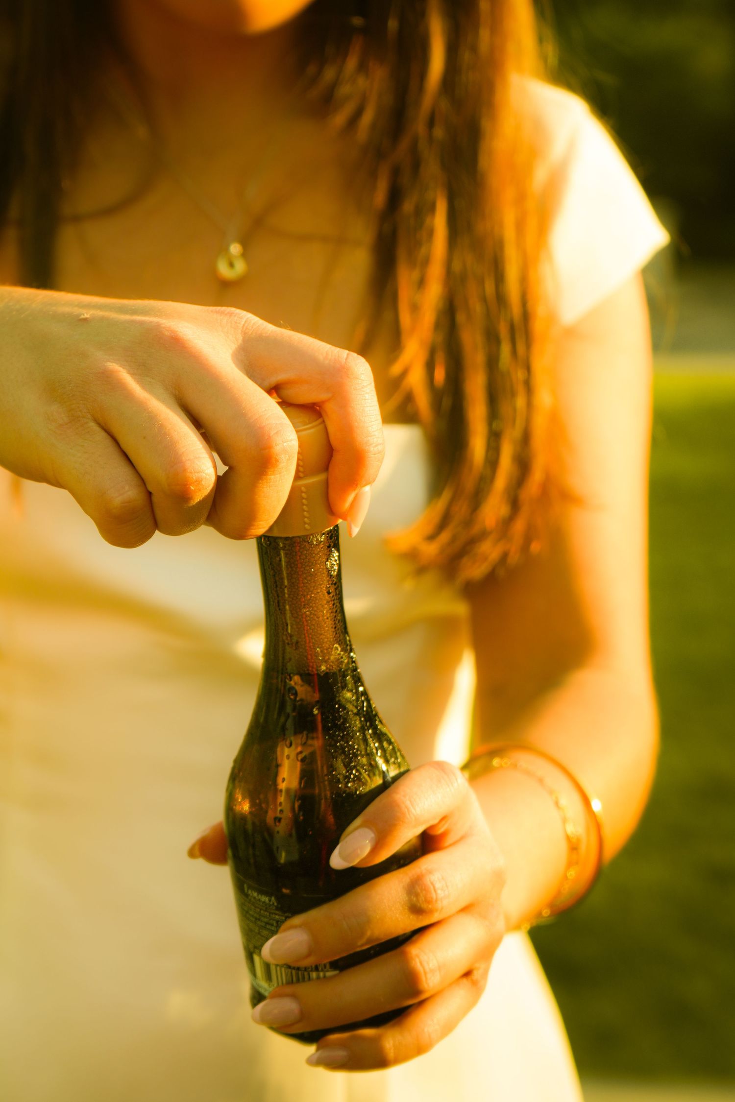 A woman opening a bottle of champagne.