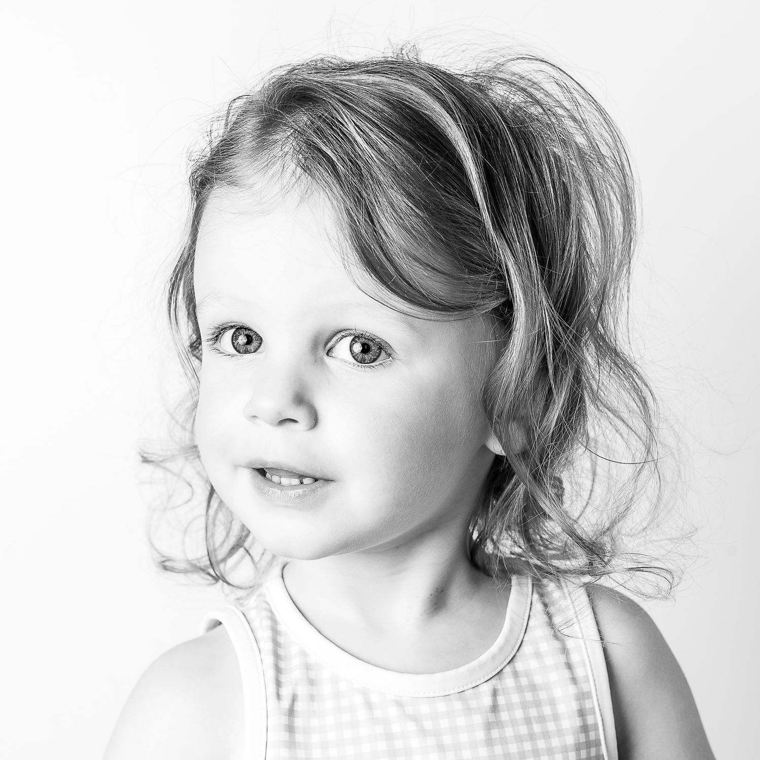 Black-and-white portrait of smiling young girl at Classic Littles children's portrait session.