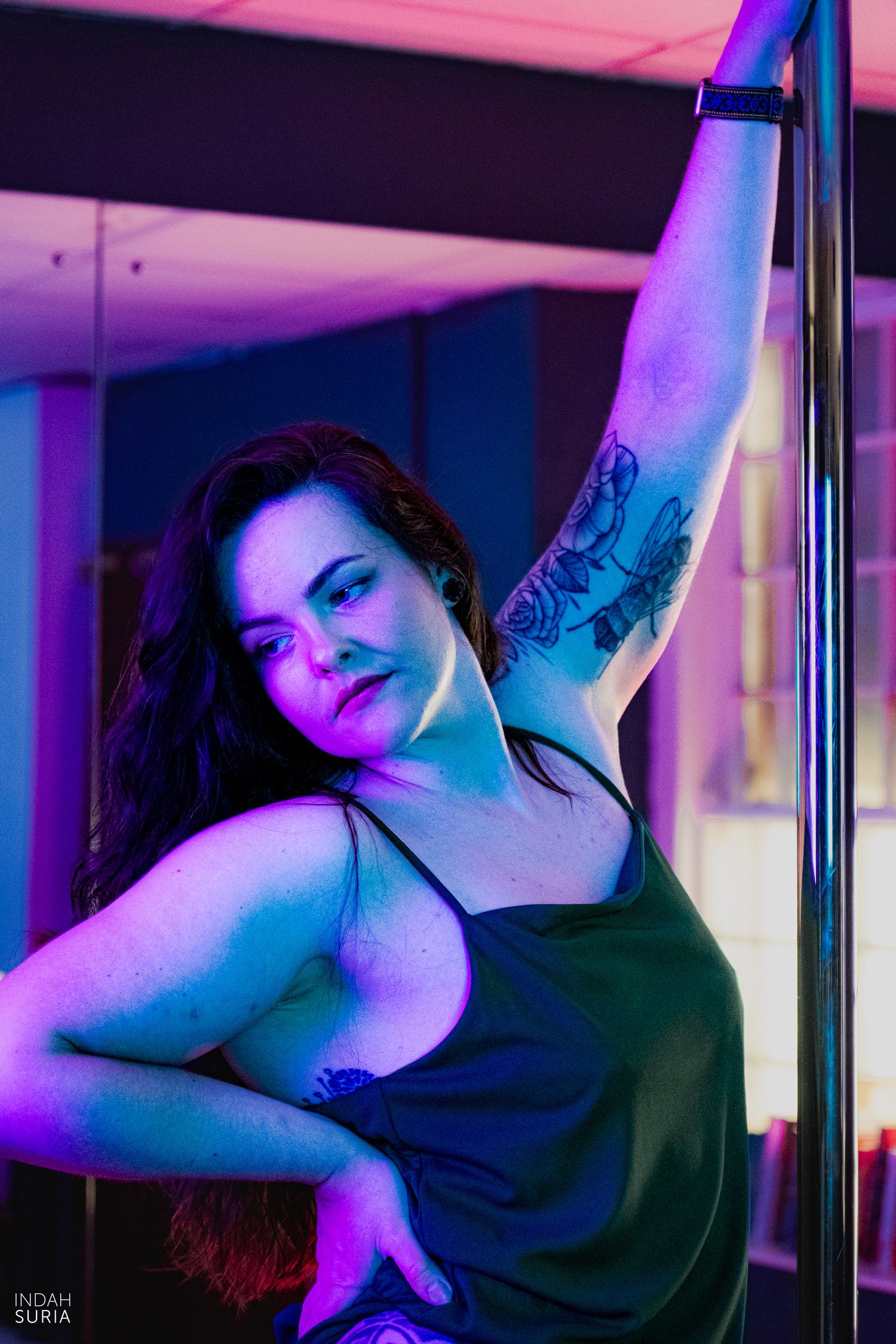 Pole dance photography where the dancer is posed in front of the pole.