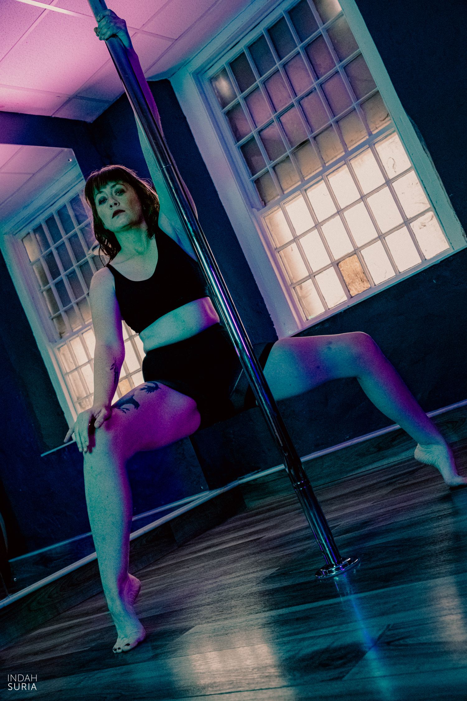Pole dance photography where the dancer is posed in front of the pole.