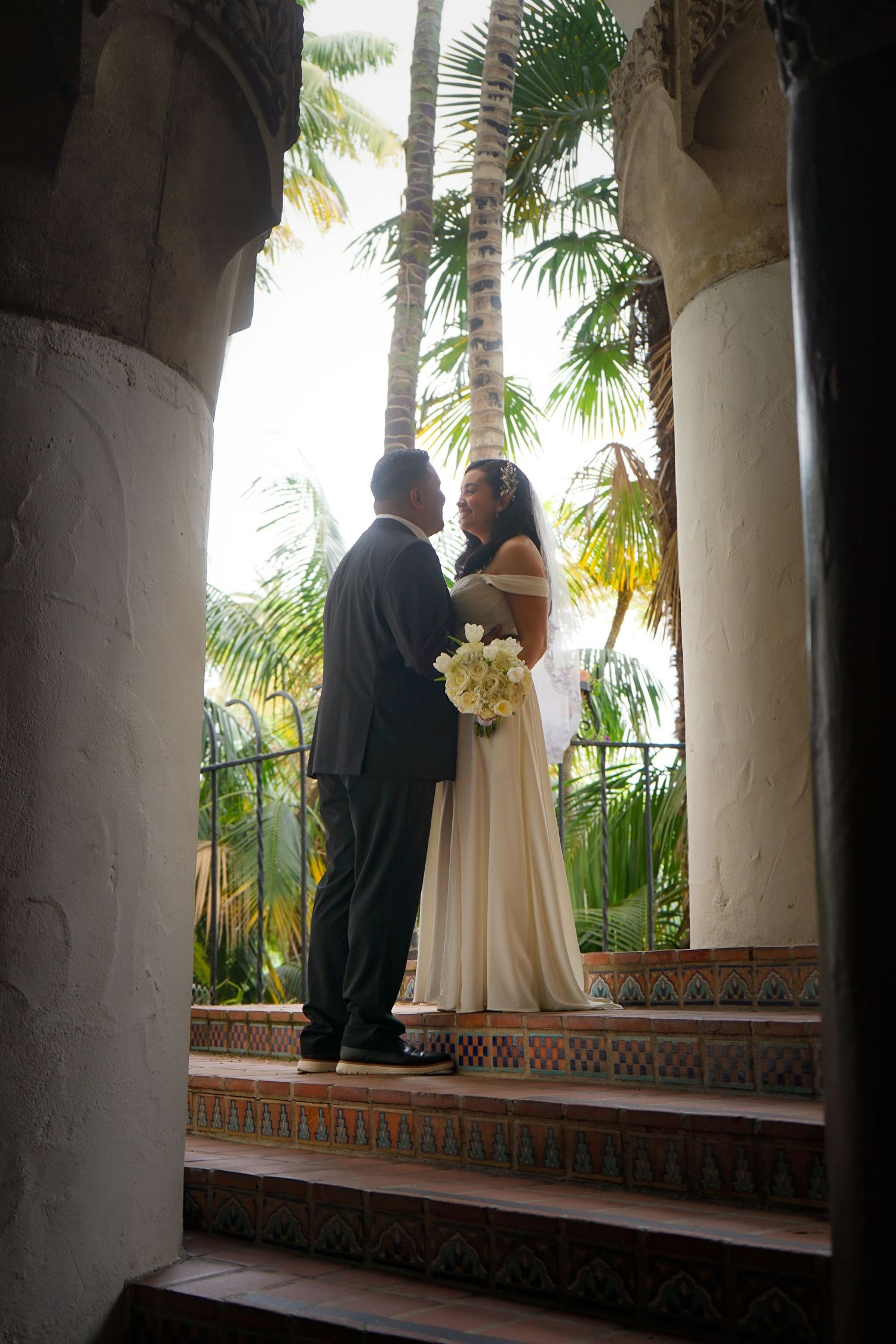 Newlyweds gazing lovingly at each other with palm trees in the background