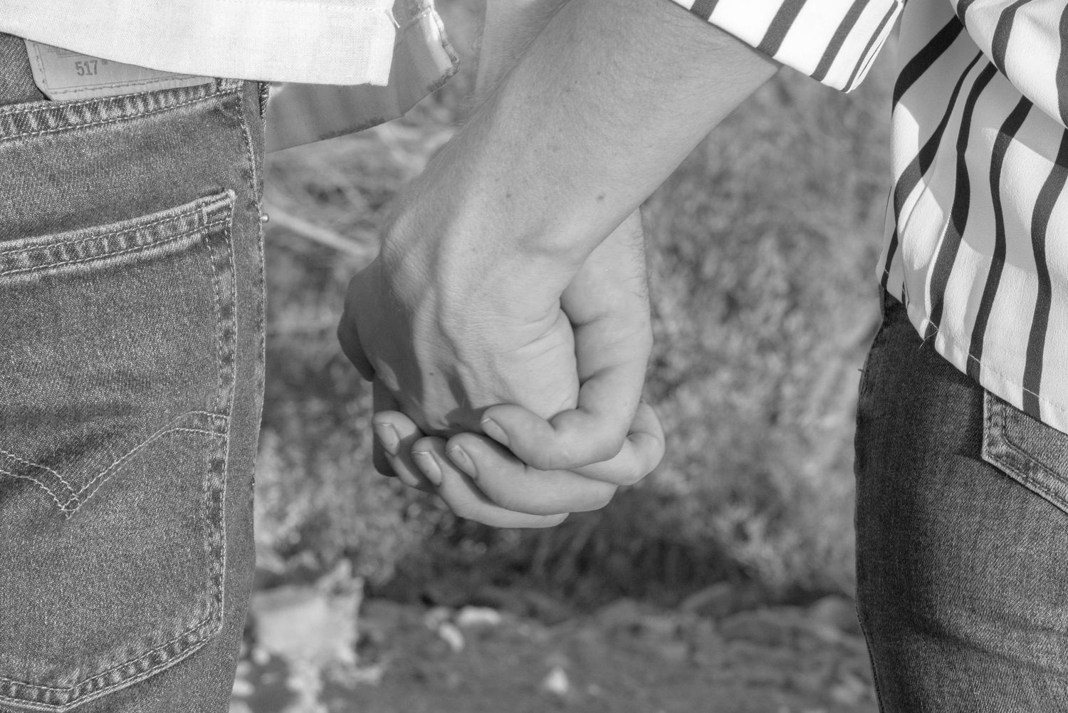 Black and white photo of a couple holding hands outdoors.
