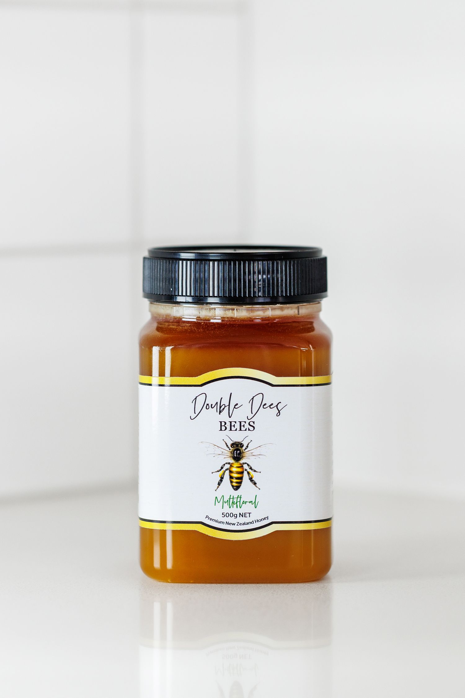 Glass jar of golden honey with minimalist bee logo branding on white label.