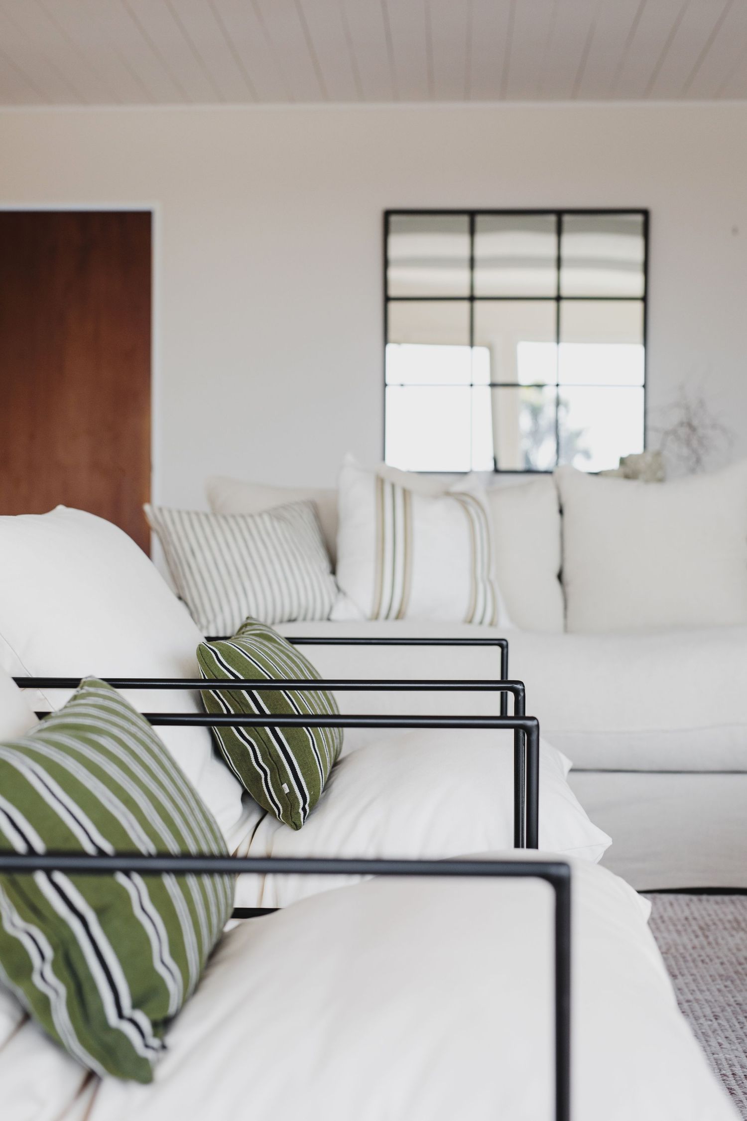Modern bedroom interior with black metal bed frame and striped green throw pillows.