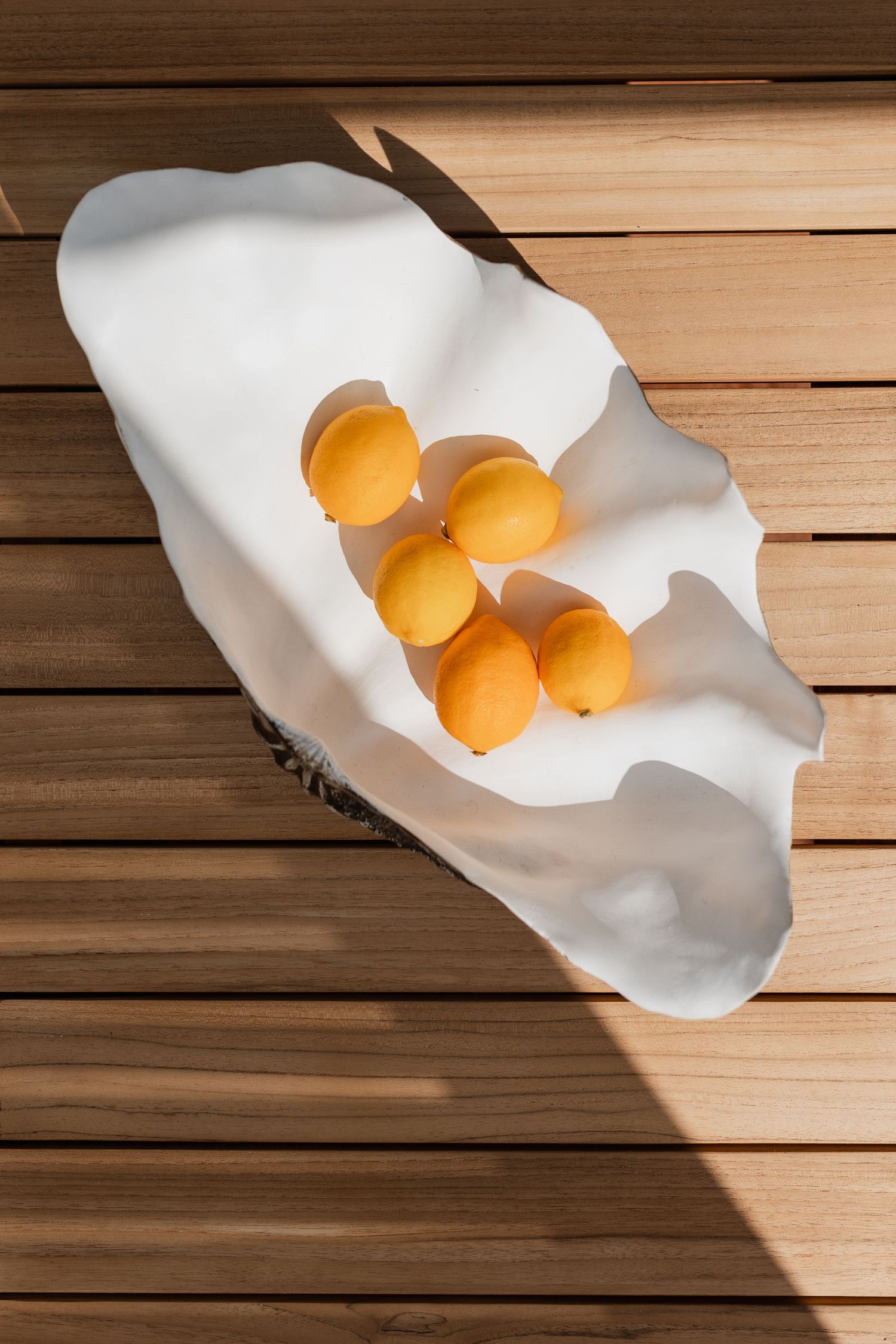 Fresh apricots arranged on a white ceramic platter on wooden decking.