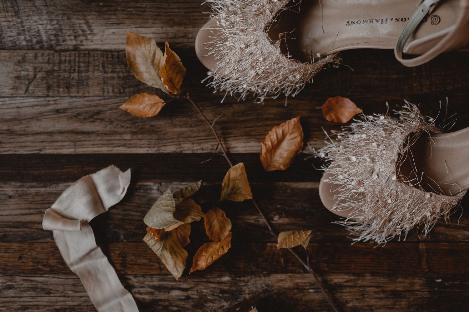 Rustic wooden surface with scattered autumn leaves and natural textiles.