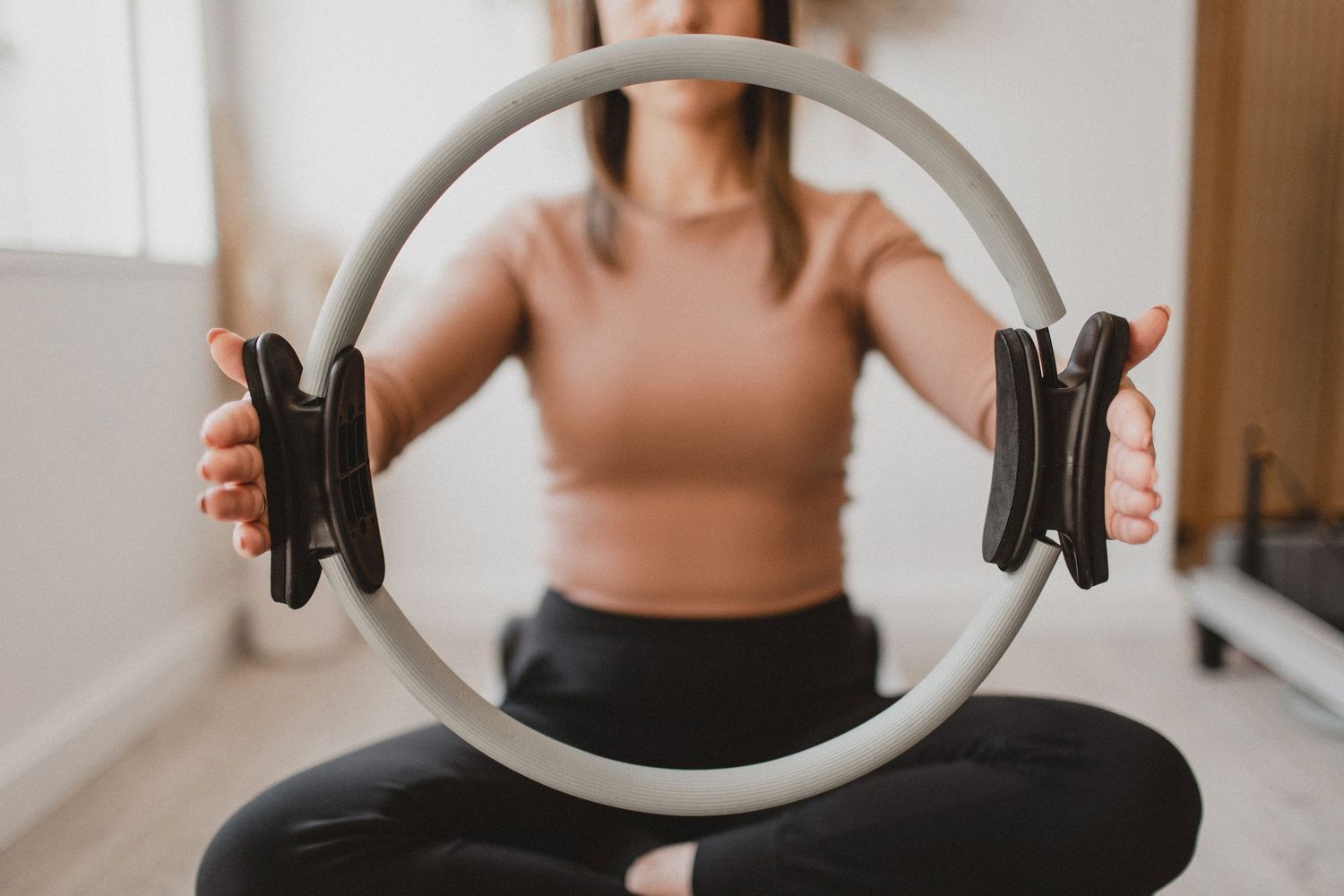Person holding a silver Pilates ring during an exercise session.