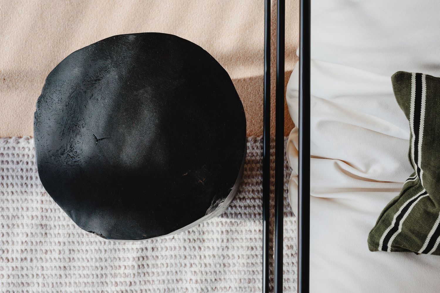 Overhead view of a black round decorative object on a textured gray rug.