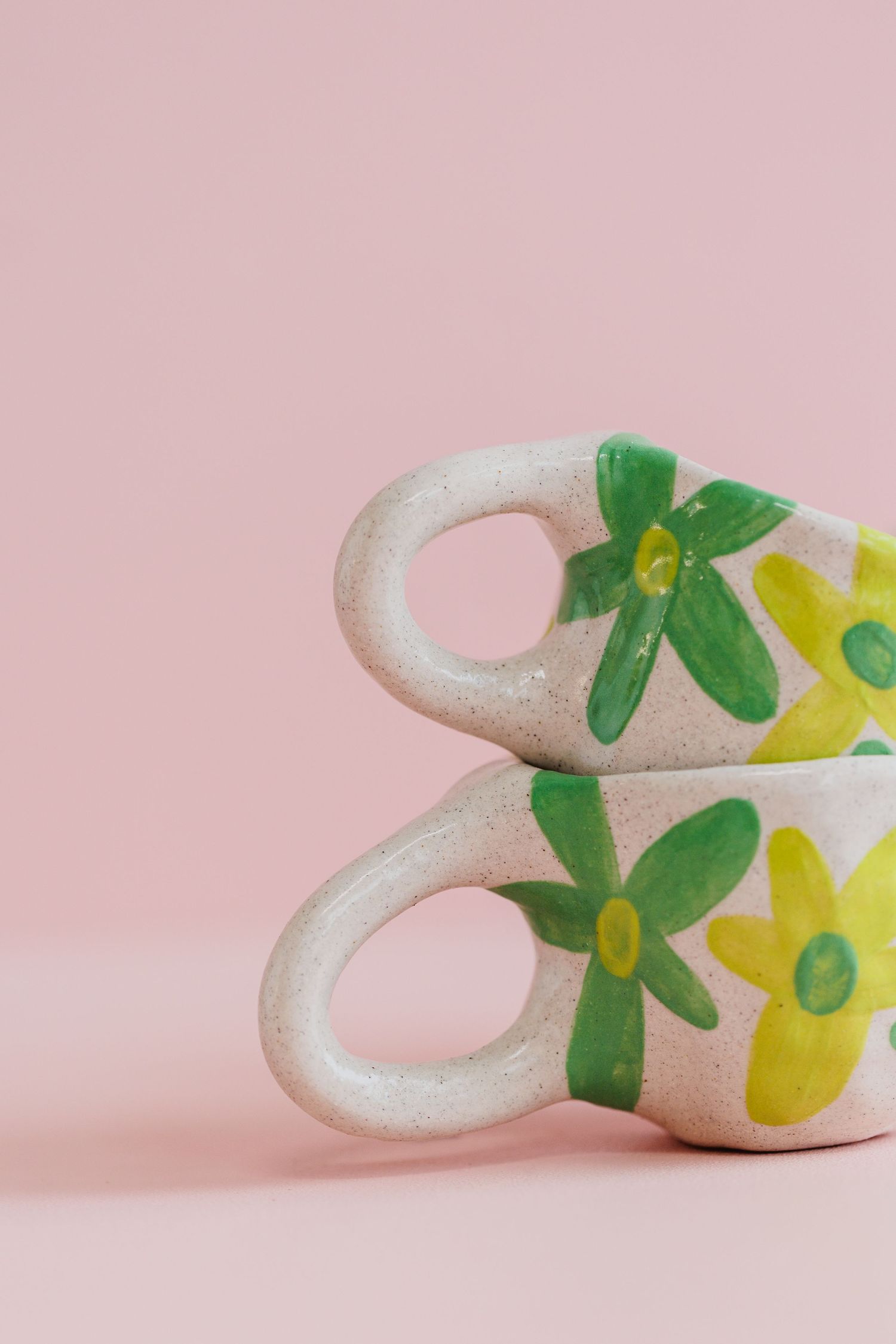 Decorative white ceramic piece with yellow flowers and green leaves against pink background.