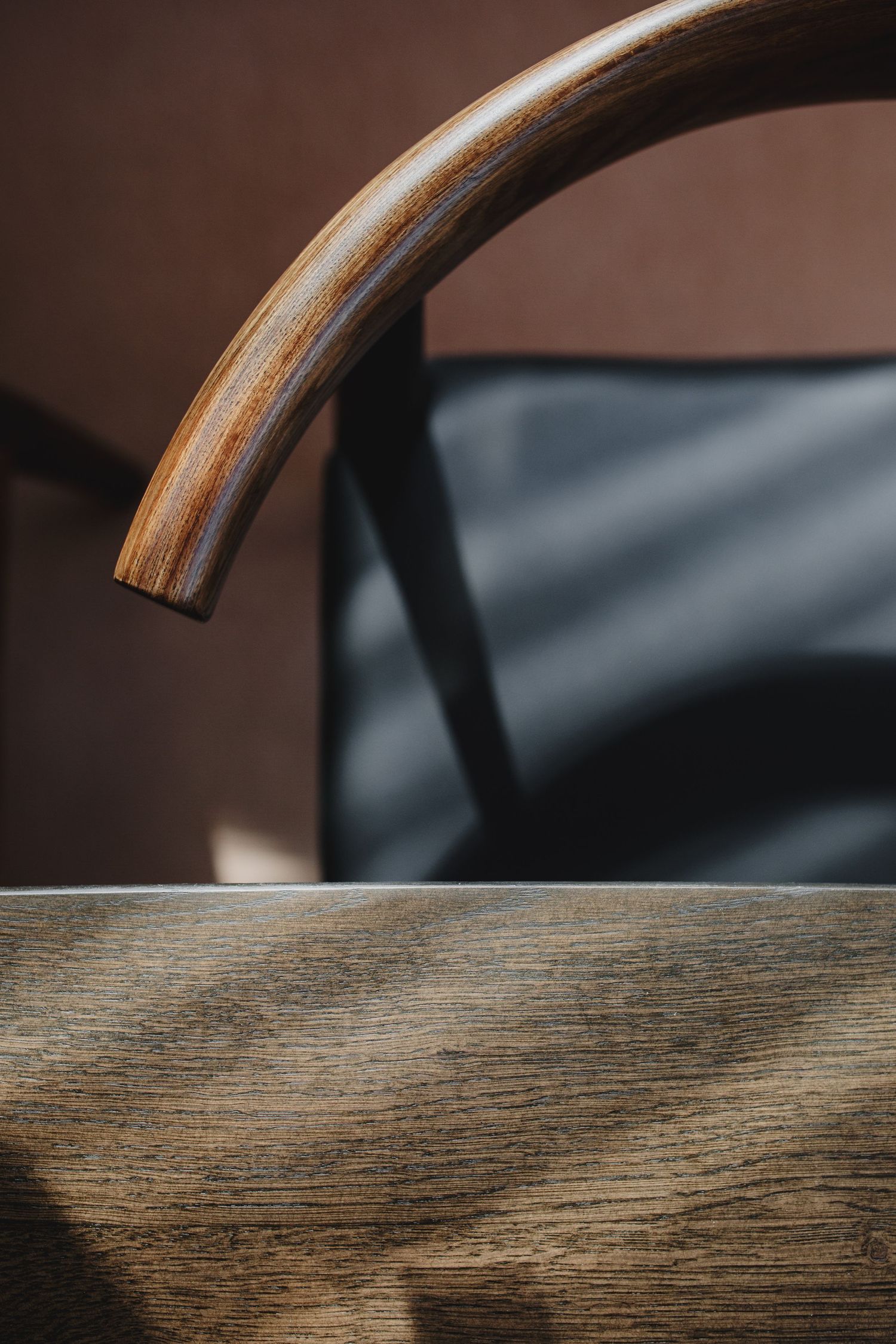 Close-up detail of curved wooden armchair showing grain texture and craftsmanship.