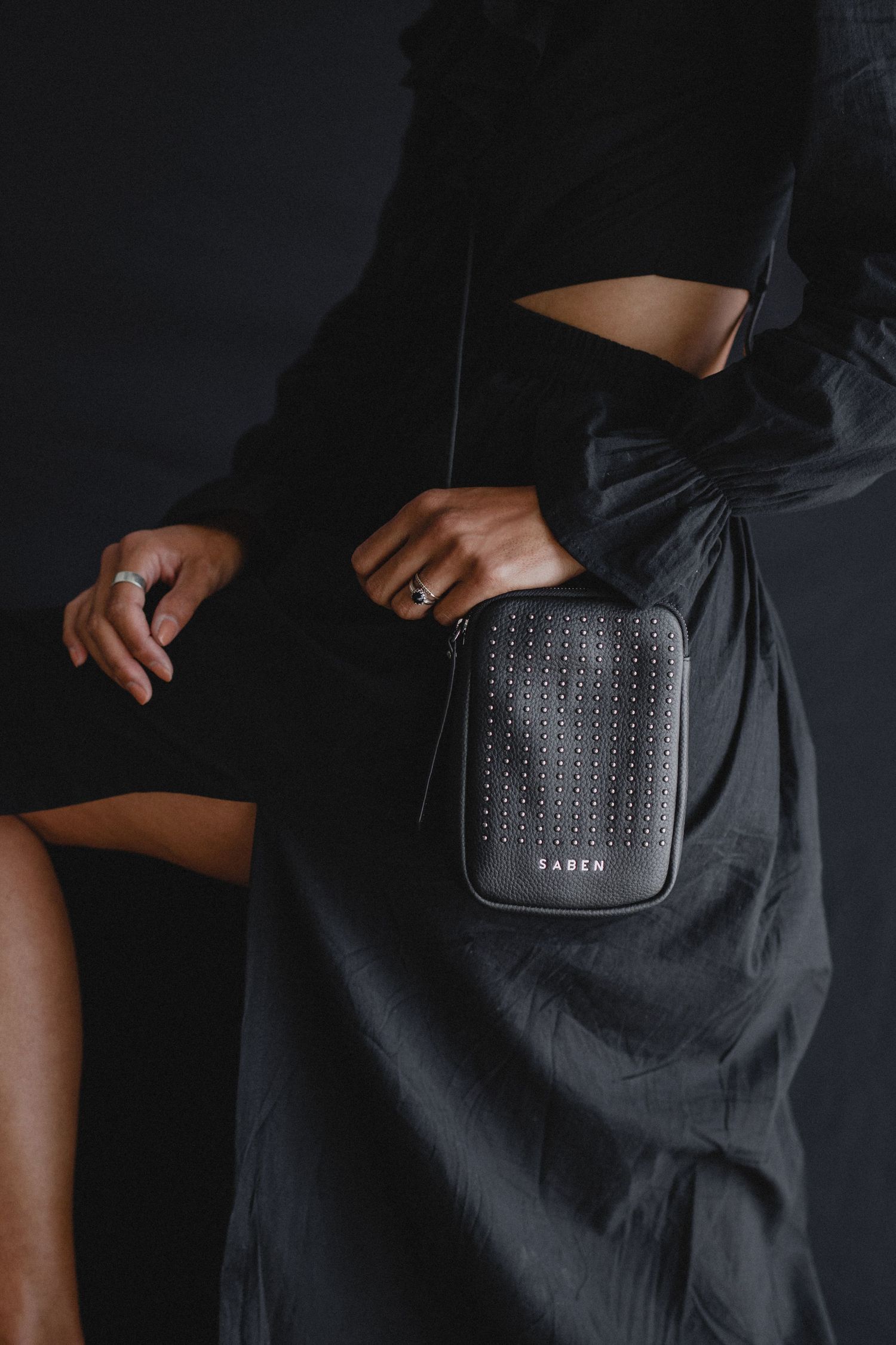 Stylish black studded crossbody bag styled with dark clothing.