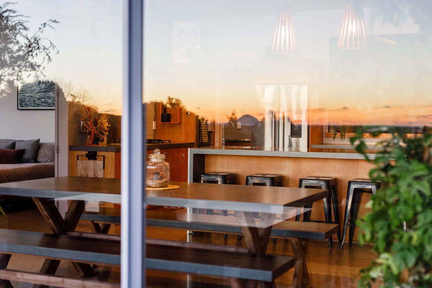 Restaurant interior with wooden benches reflected in window during sunset.