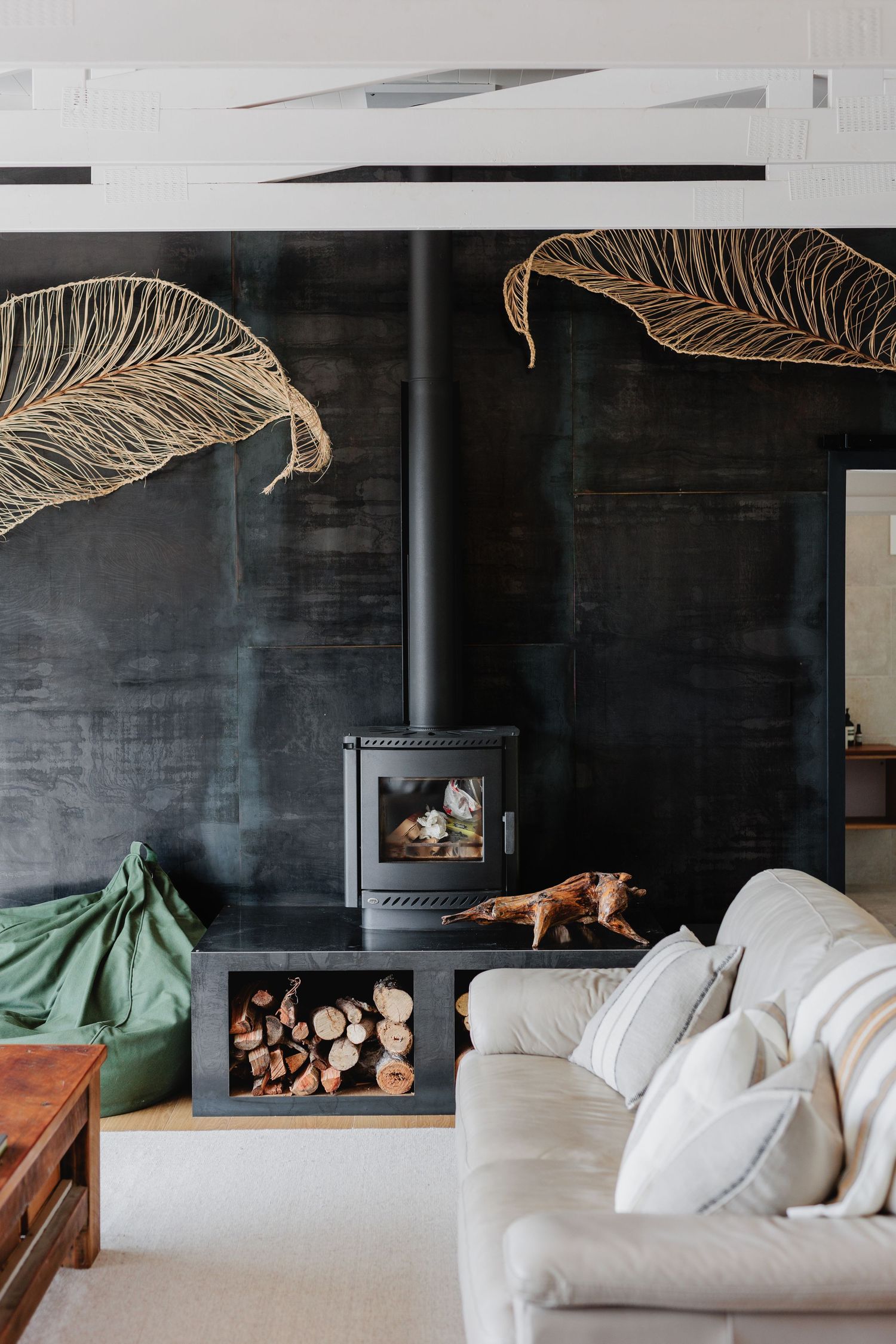 Contemporary living room with black accent wall featuring gold leaf designs and wood burning stove.