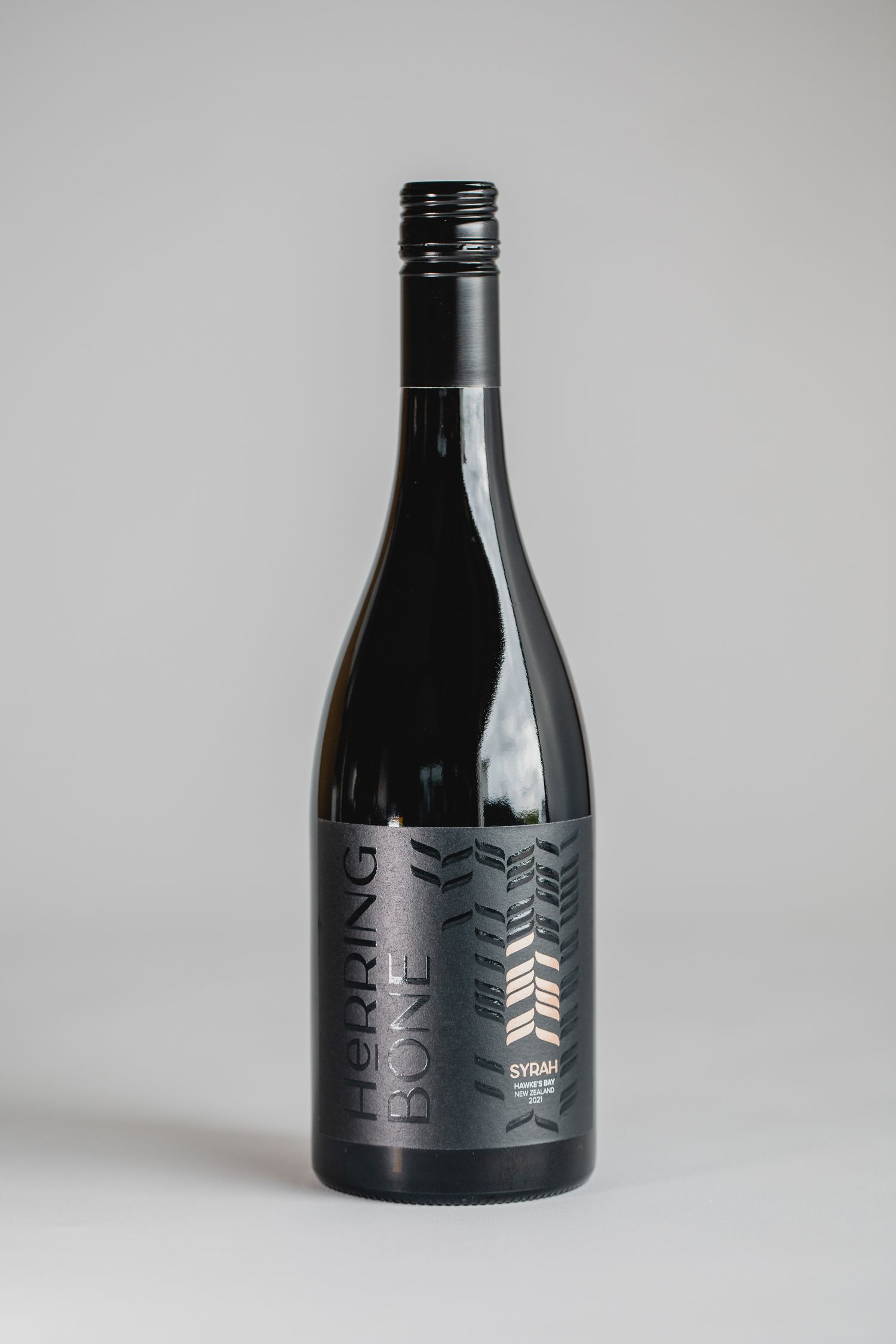Sleek black wine bottle with modern geometric pattern design on gray background.