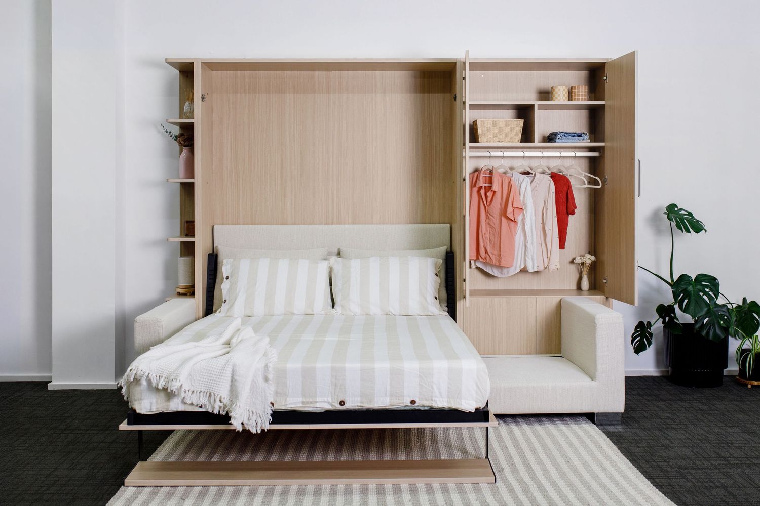 Modern murphy bed with built-in storage and wardrobe in light wood finish.