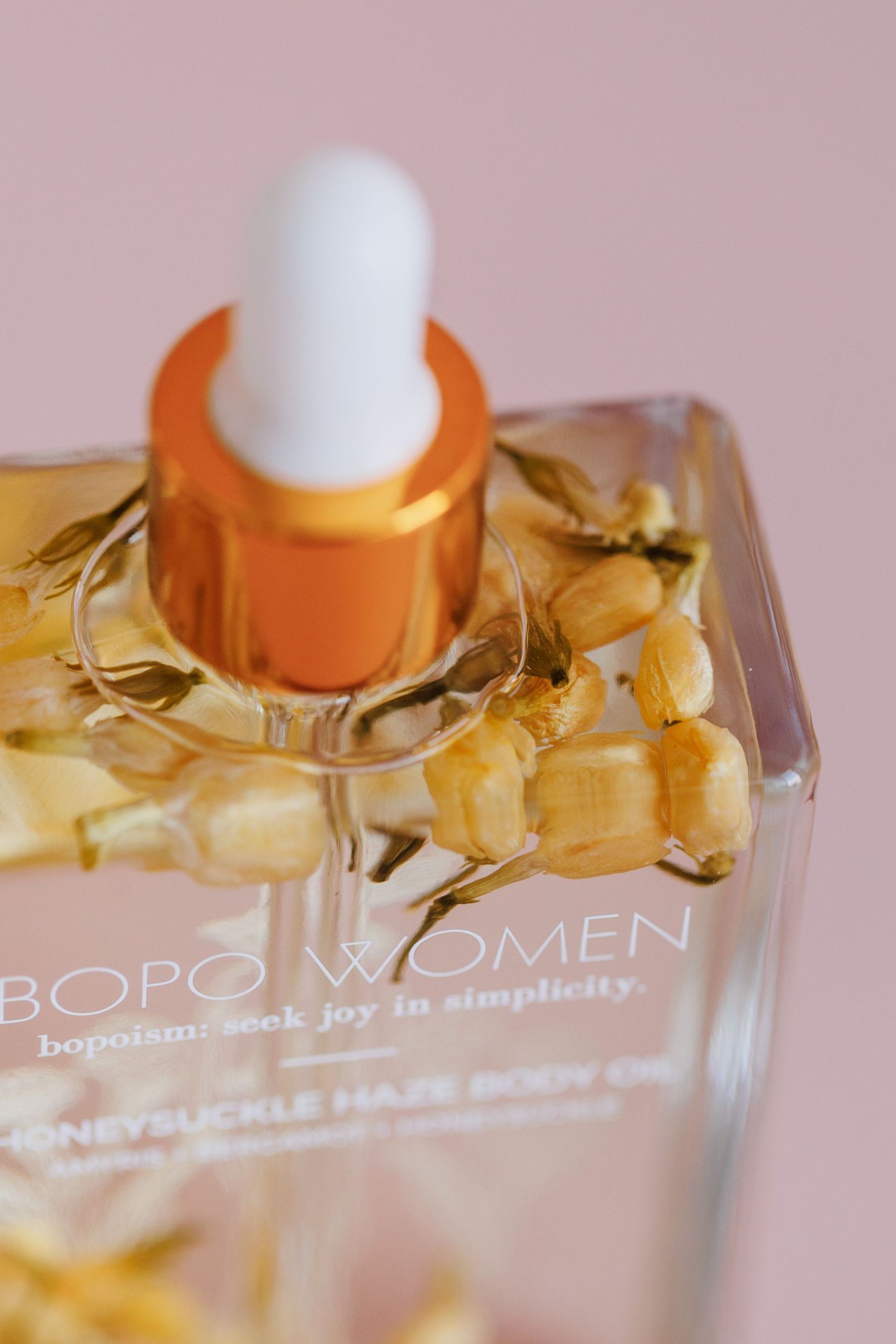 Close-up of a BOPO Women serum dropper bottle with gold floral decorative elements.