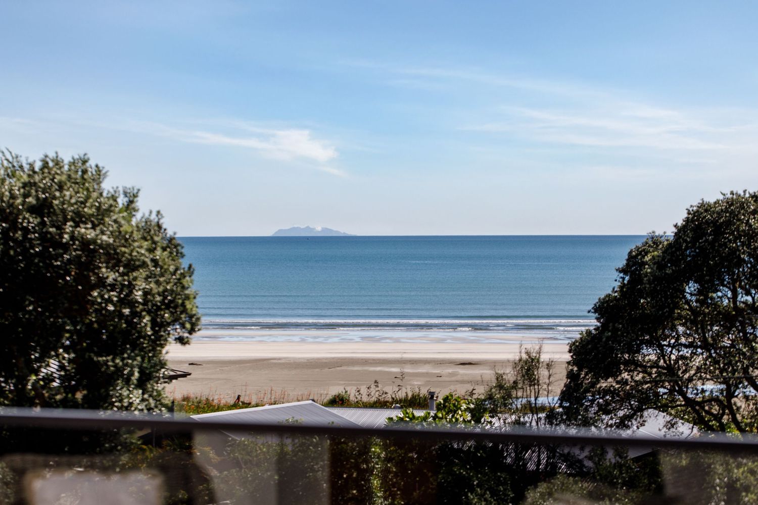 Scenic coastal landscape with blue ocean waters and sandy beach stretching to the horizon.