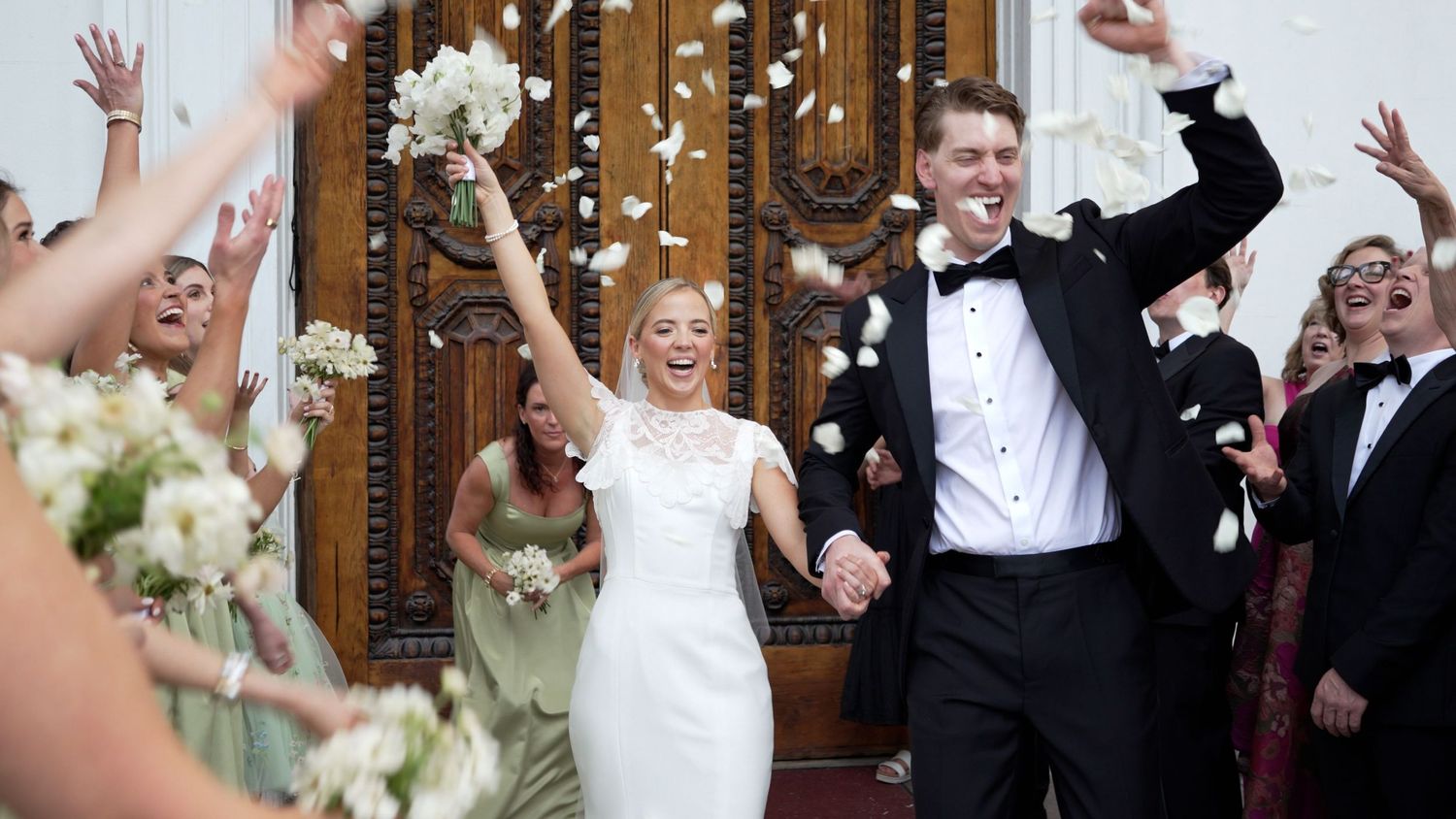 Laura Smith and Caleb Connerty leaving a chapel in Charleston, South Carolina on their wedding day. Flower petals are thrown in the air.