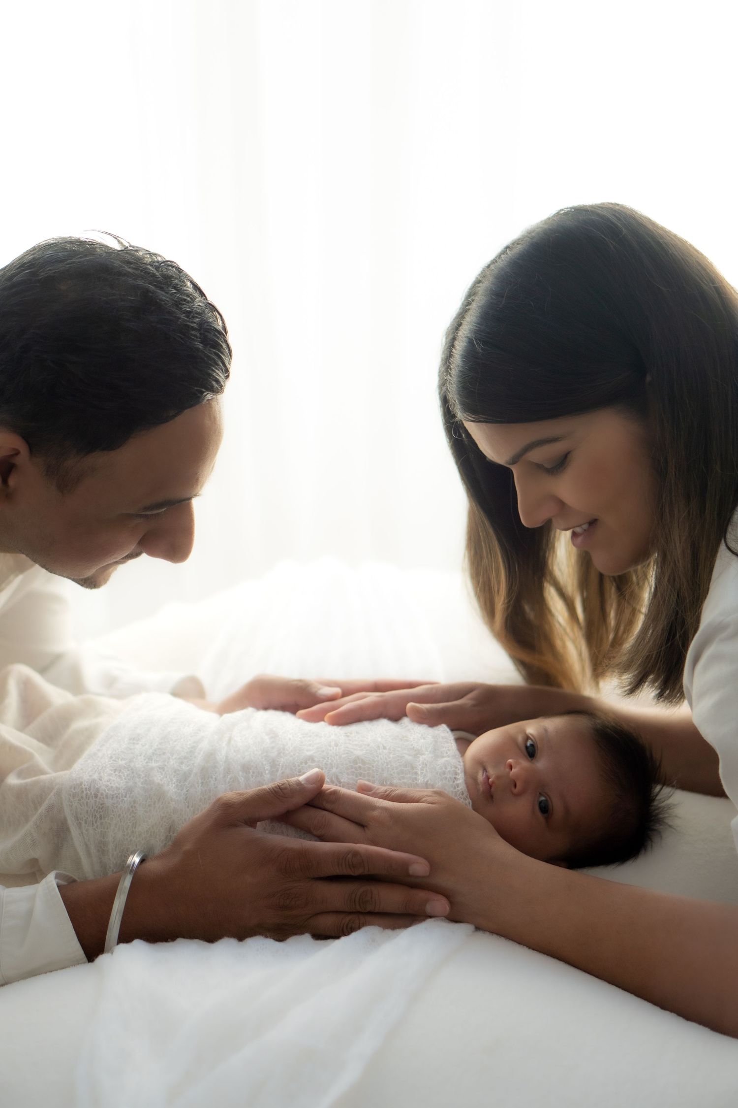 Family embracing their newborn baby during a professional newborn photoshoot.