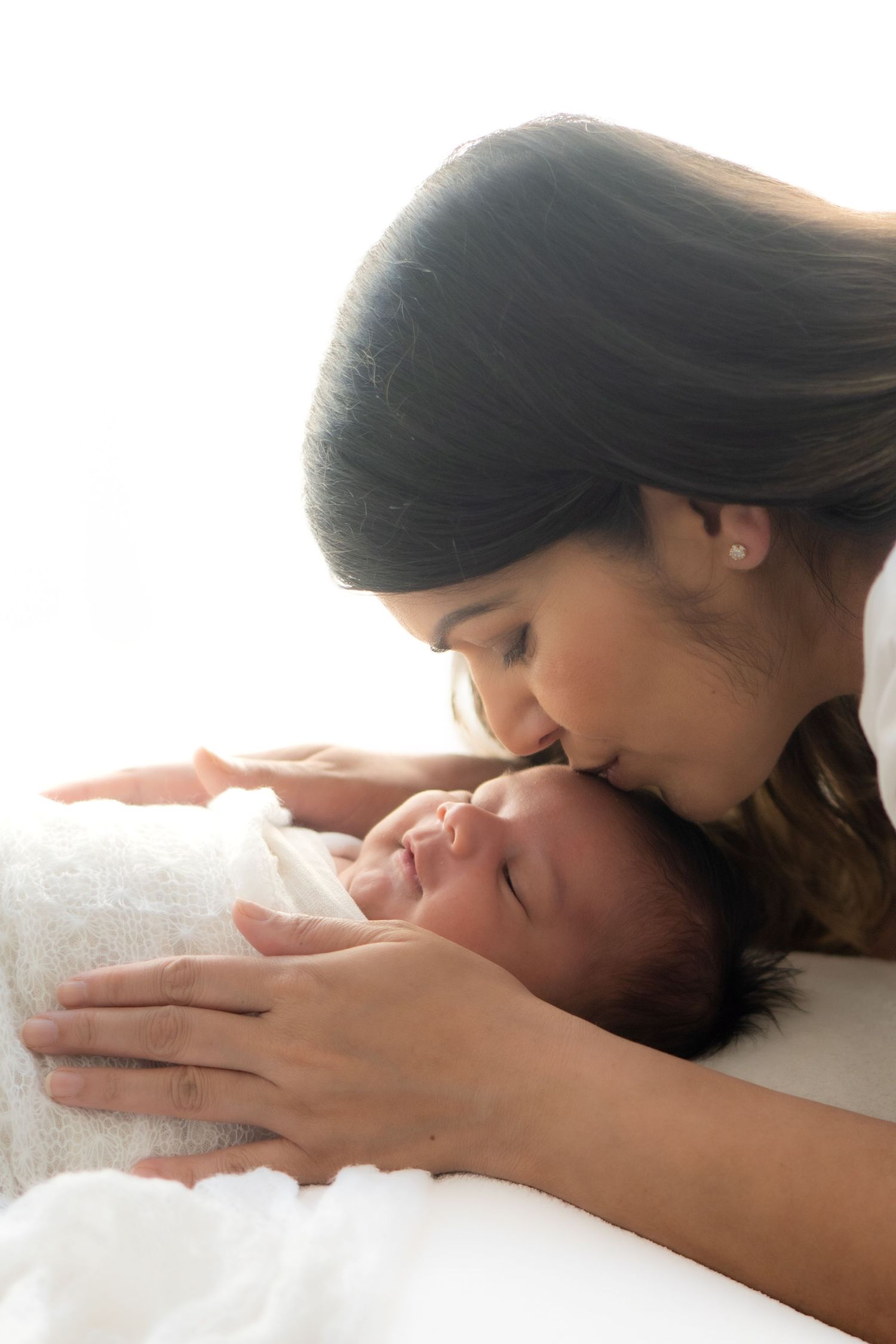 Mum cuddling her sleeping newborn in a neutral photography studio in Melbourne.
