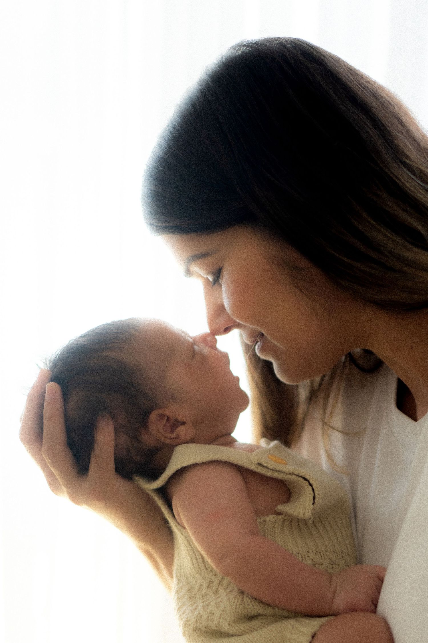 New mum embracing her newborn baby during a professional newborn photoshoot in Melbourne