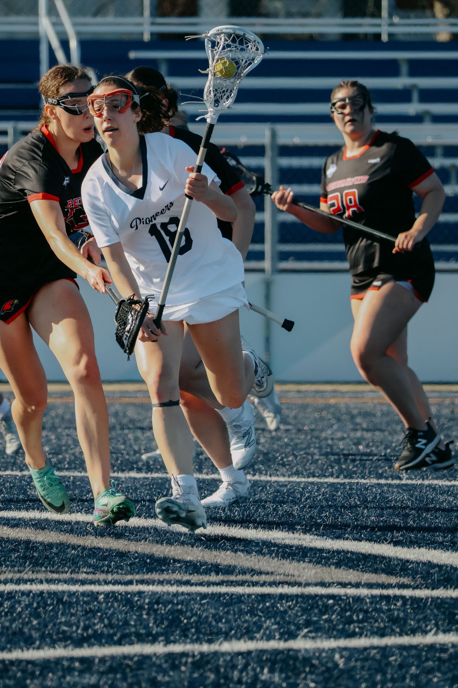 Female lacrosse player in white uniform drives past a defender during an outdoor game.