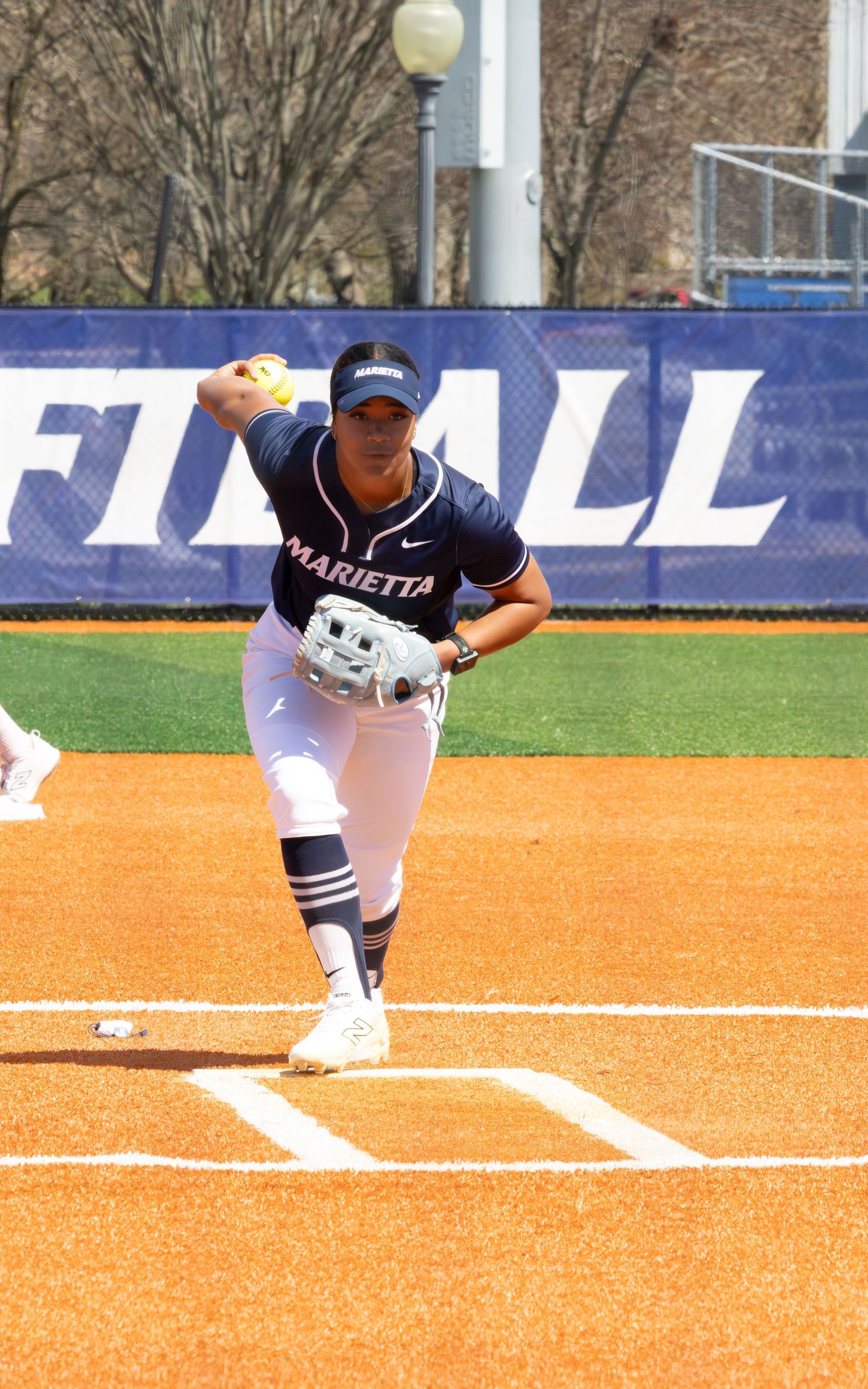 Marietta College softball pitcher winds up to throw during a sunny outdoor game.