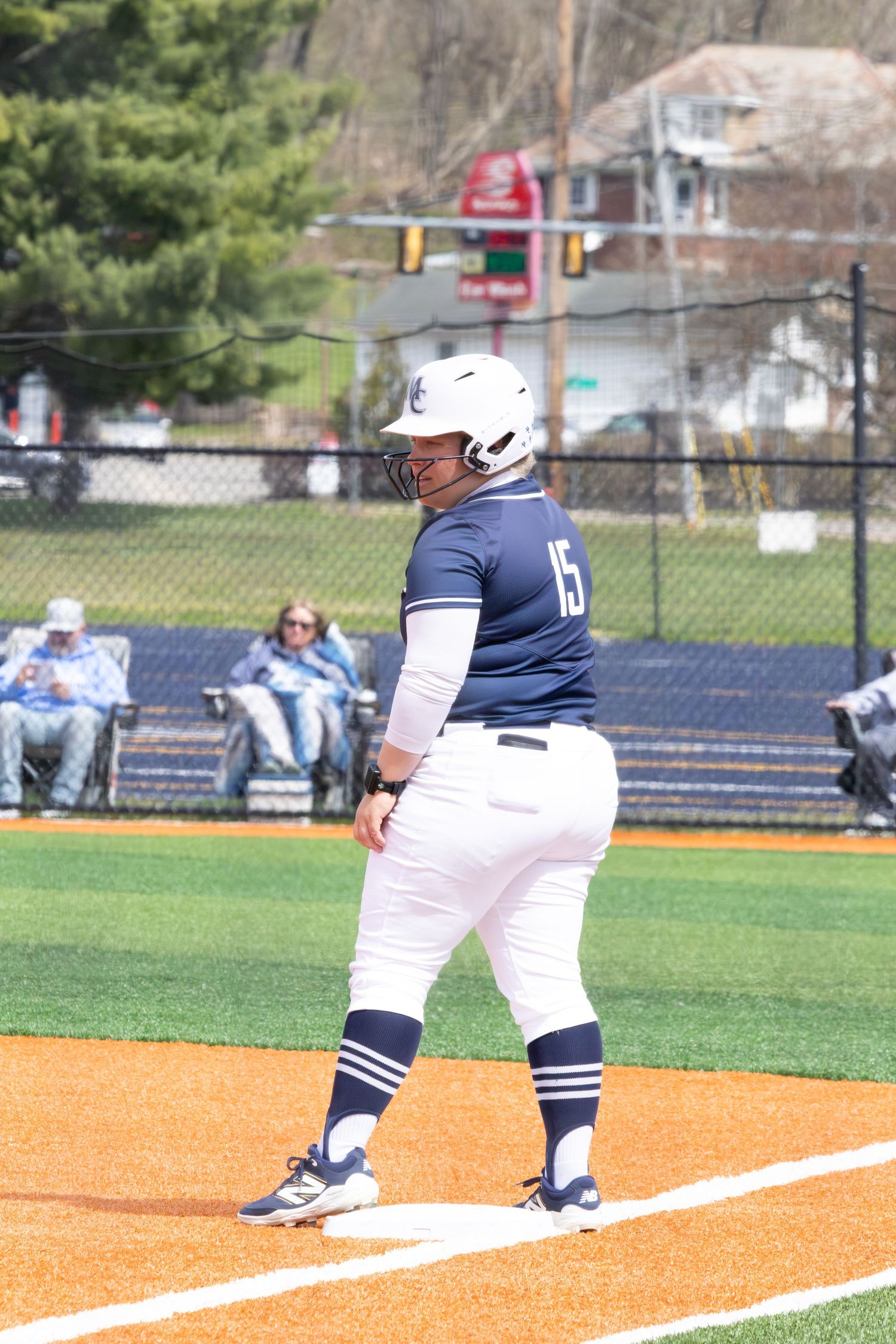 Female softball player in Marietta College uniform stands ready at first base during a game.