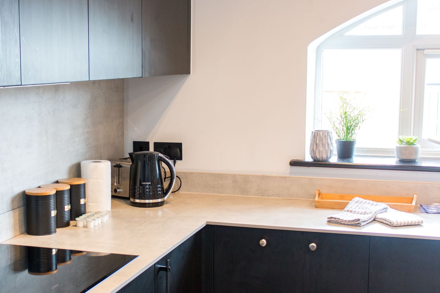Modern black and white kitchen with long countertop and window lighting.