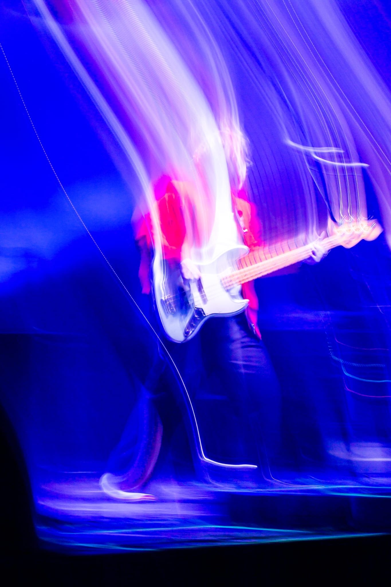 Abstract light trails in blue and pink create motion blur effect during performance.