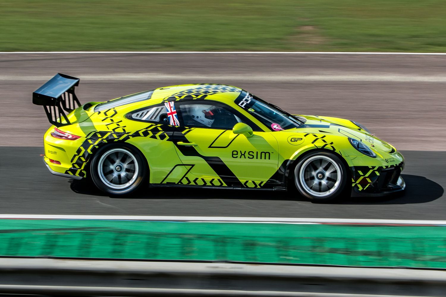 Lime green Porsche 911 GT3 Cup with Exsim livery racing on a circuit track.