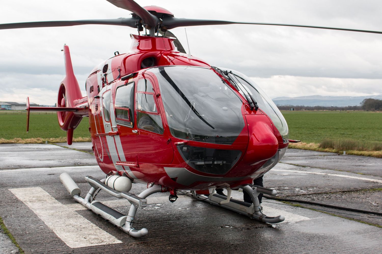 Red emergency helicopter positioned on helipad ready for takeoff.