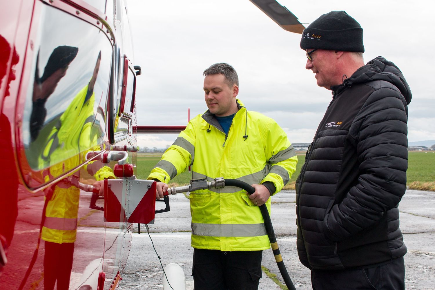 Aviation crew members inspecting helicopter components in high visibility gear.