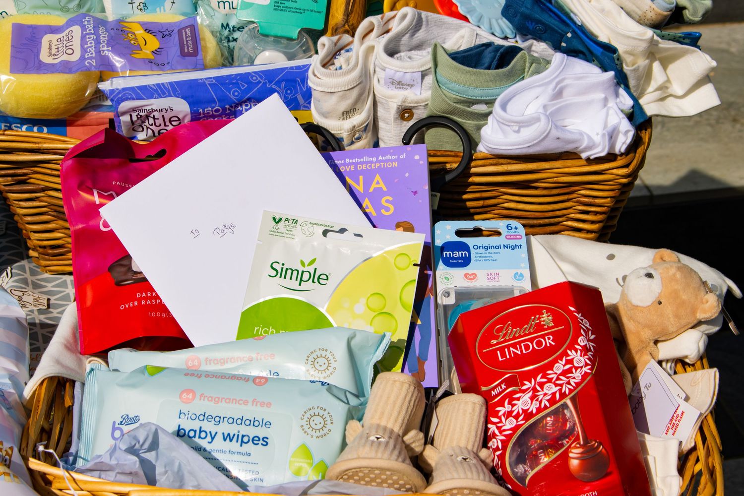 Overhead view of wipes, diapers and baby products in wicker basket.