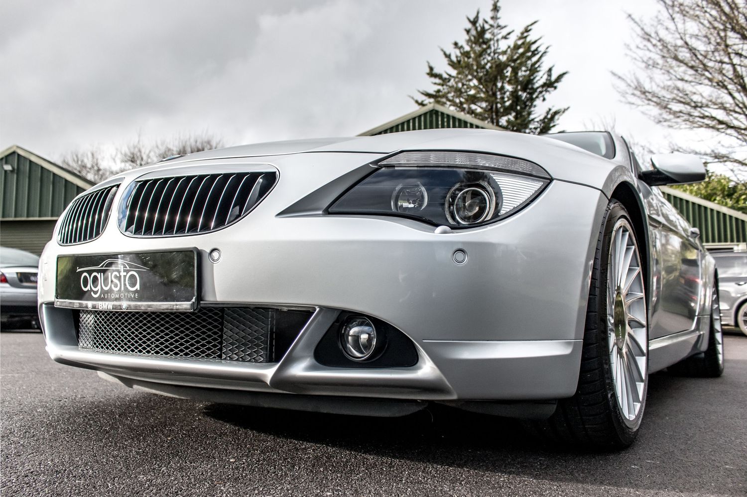 Silver BMW 6 Series coupe showcasing sleek front fascia, chrome grille, and stylish alloy wheels in outdoor setting.