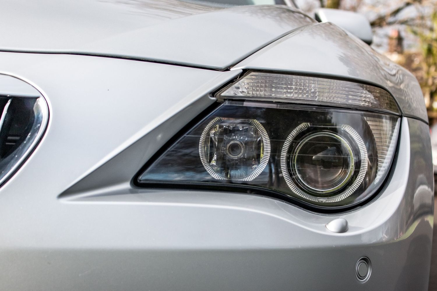 Close-up of a BMW angel eye headlight on a silver car, showcasing sleek automotive design.