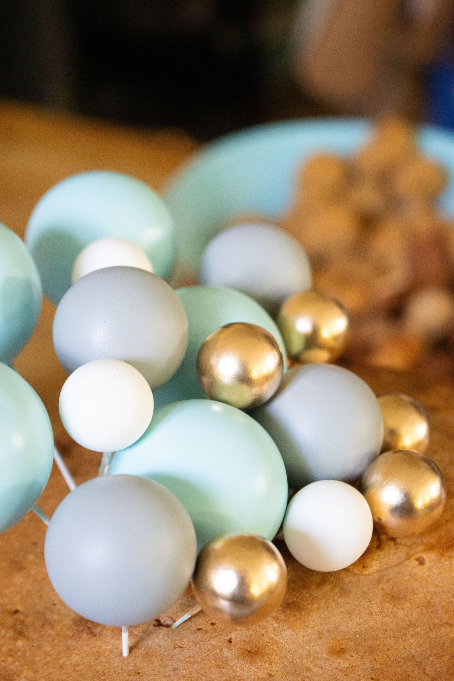 White and gold decorative Christmas ornament balls arranged on a brown surface.