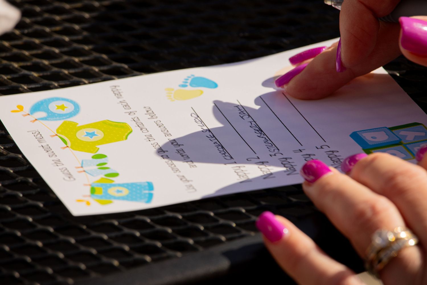 Hands filling out colorful baby-themed cards or documents.