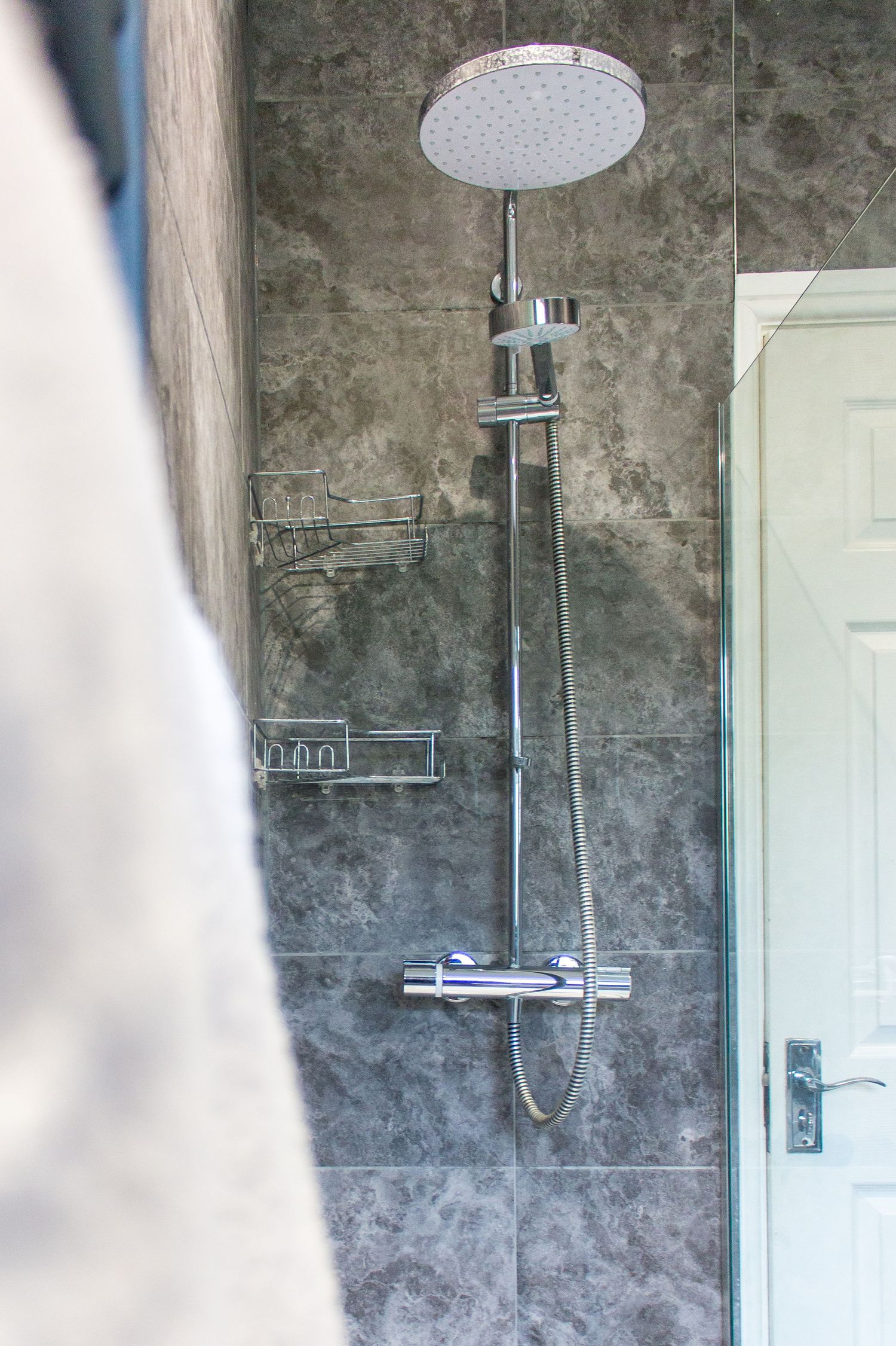 Industrial-style bathroom with concrete-effect walls and modern rainfall shower fixture.