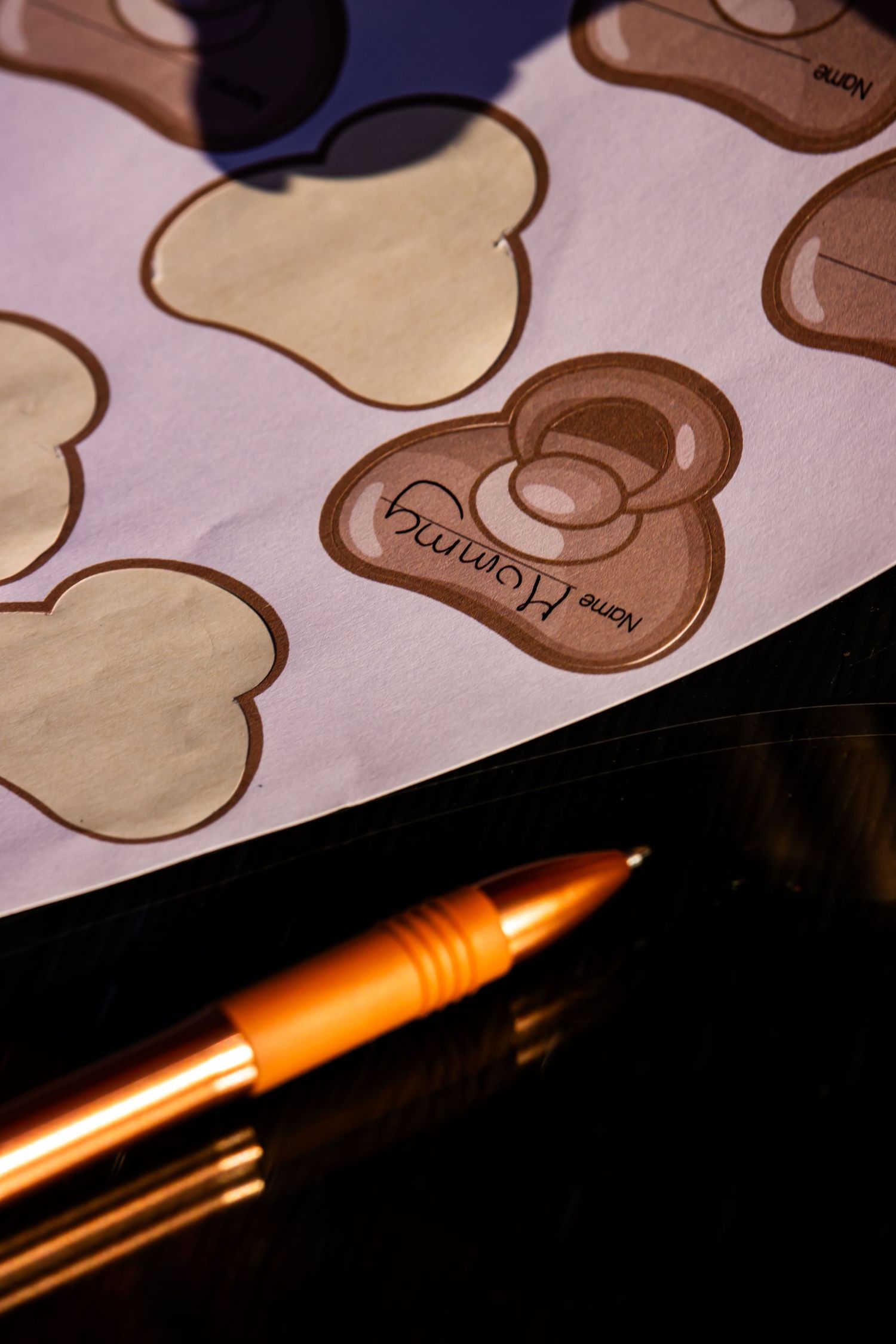 Orange pen lies against paper with brown illustrated designs in warm lighting.