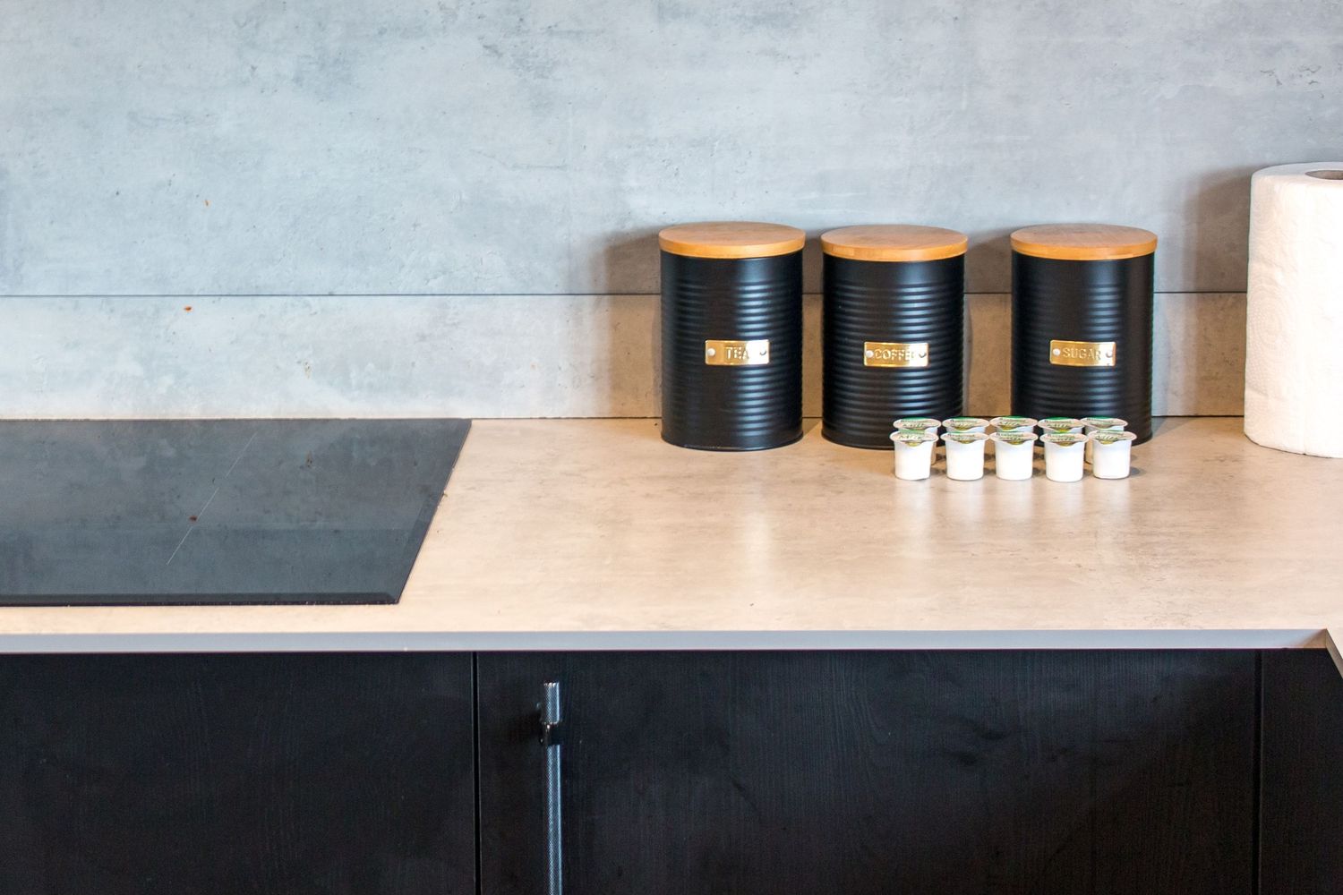 Minimalist kitchen countertop with black storage containers arranged in a row.