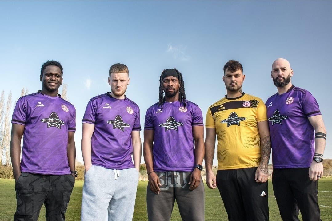 Soccer team members in purple jerseys posing together on field.