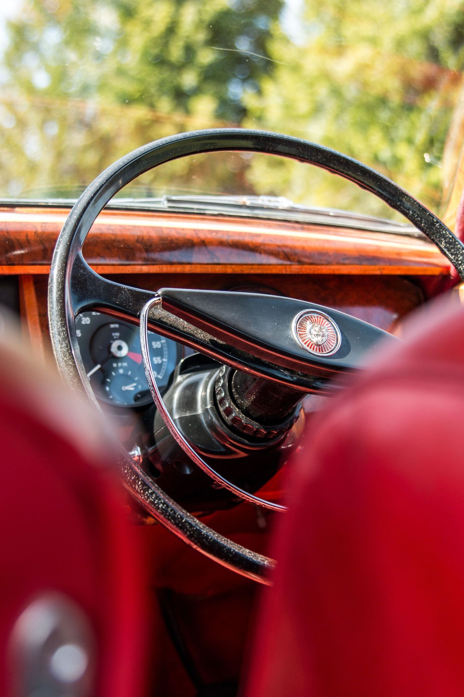 Interior dashboard view of classic car with wooden steering wheel.