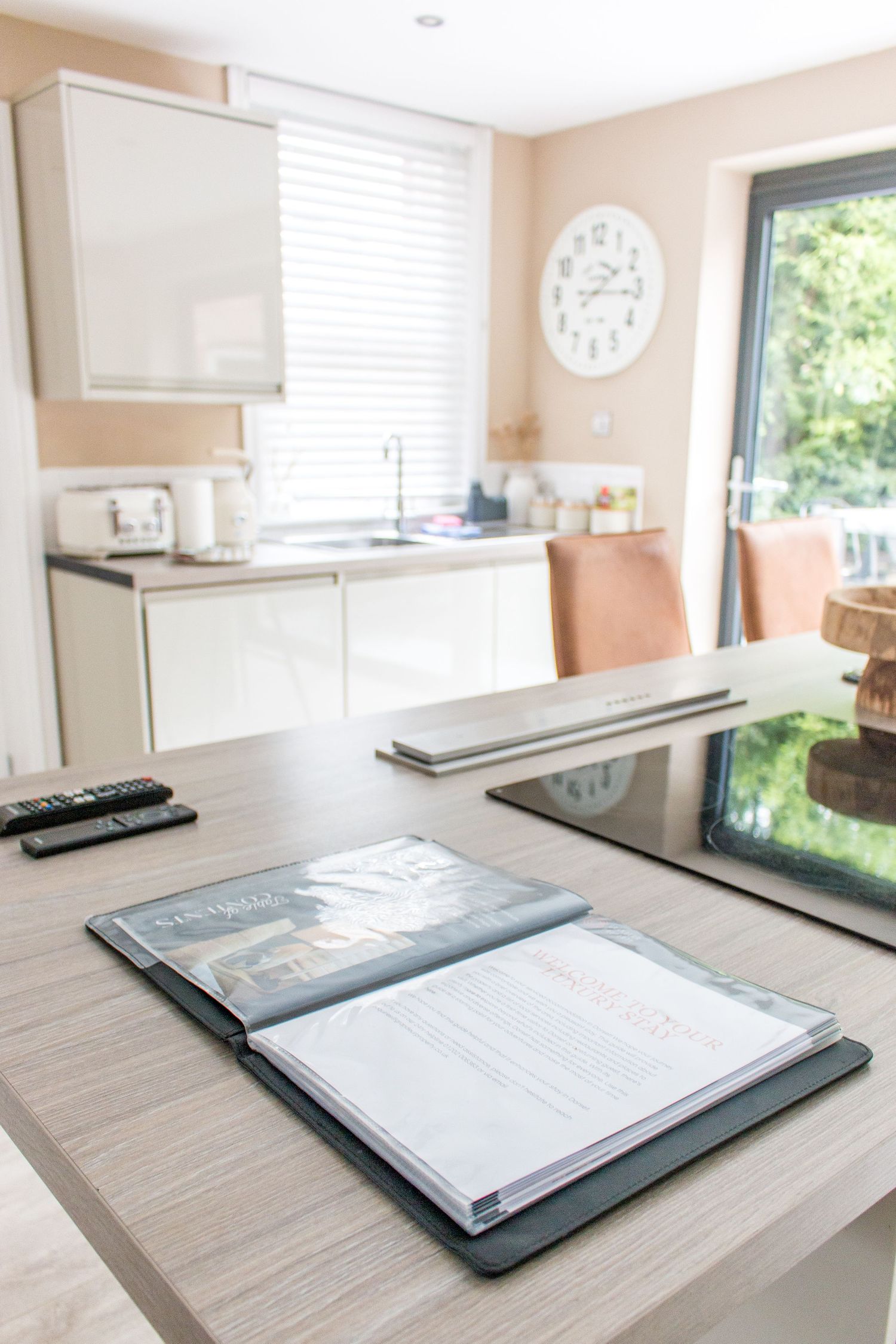 Clean modern kitchen with information binder on wooden countertop near window.