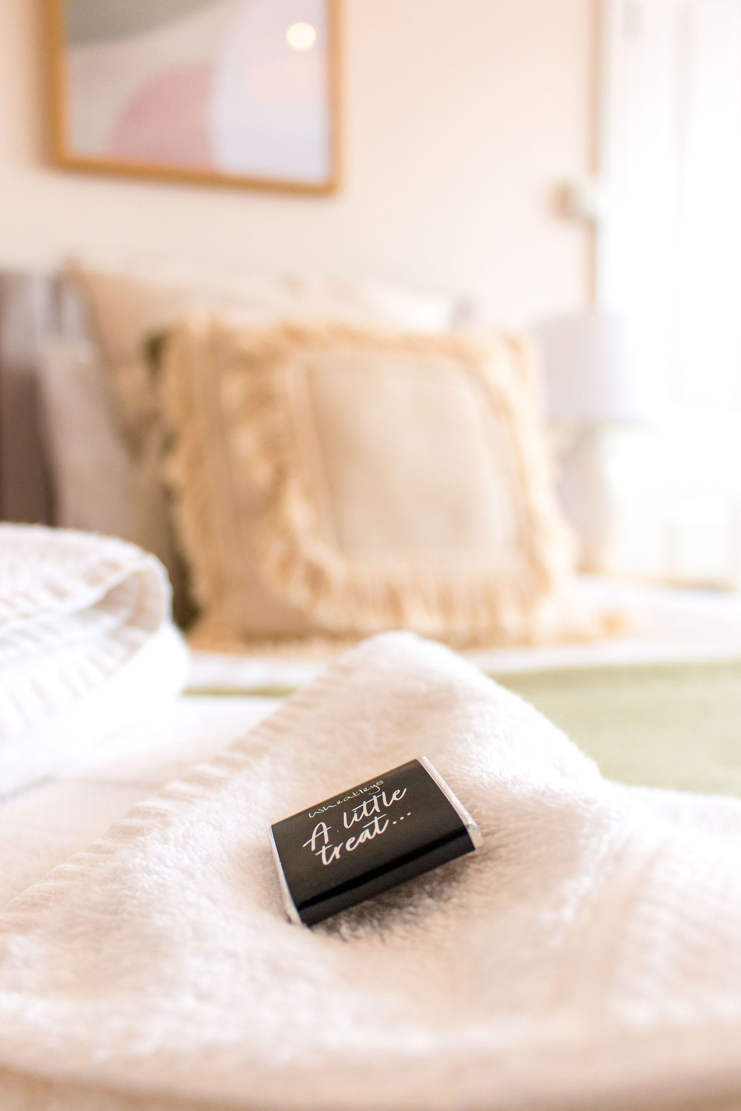 Close-up view of white bedding with small black name tags in a minimalist bedroom setting.